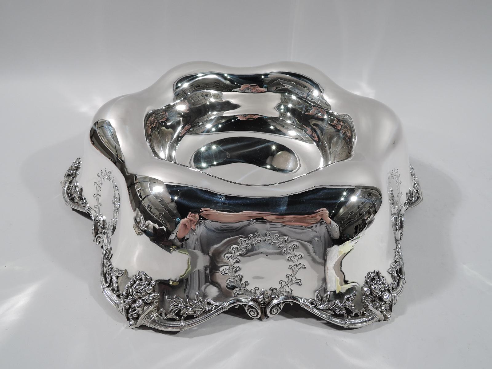 Edwardian Regency sterling silver centerpiece bowl. Made by Redlich in New York, circa 1910. Round and deep well with waving rolled edge engraved with laurel wreaths. Scrolled cornucopia applied to rim. Substantial with nice heft. Fully marked
