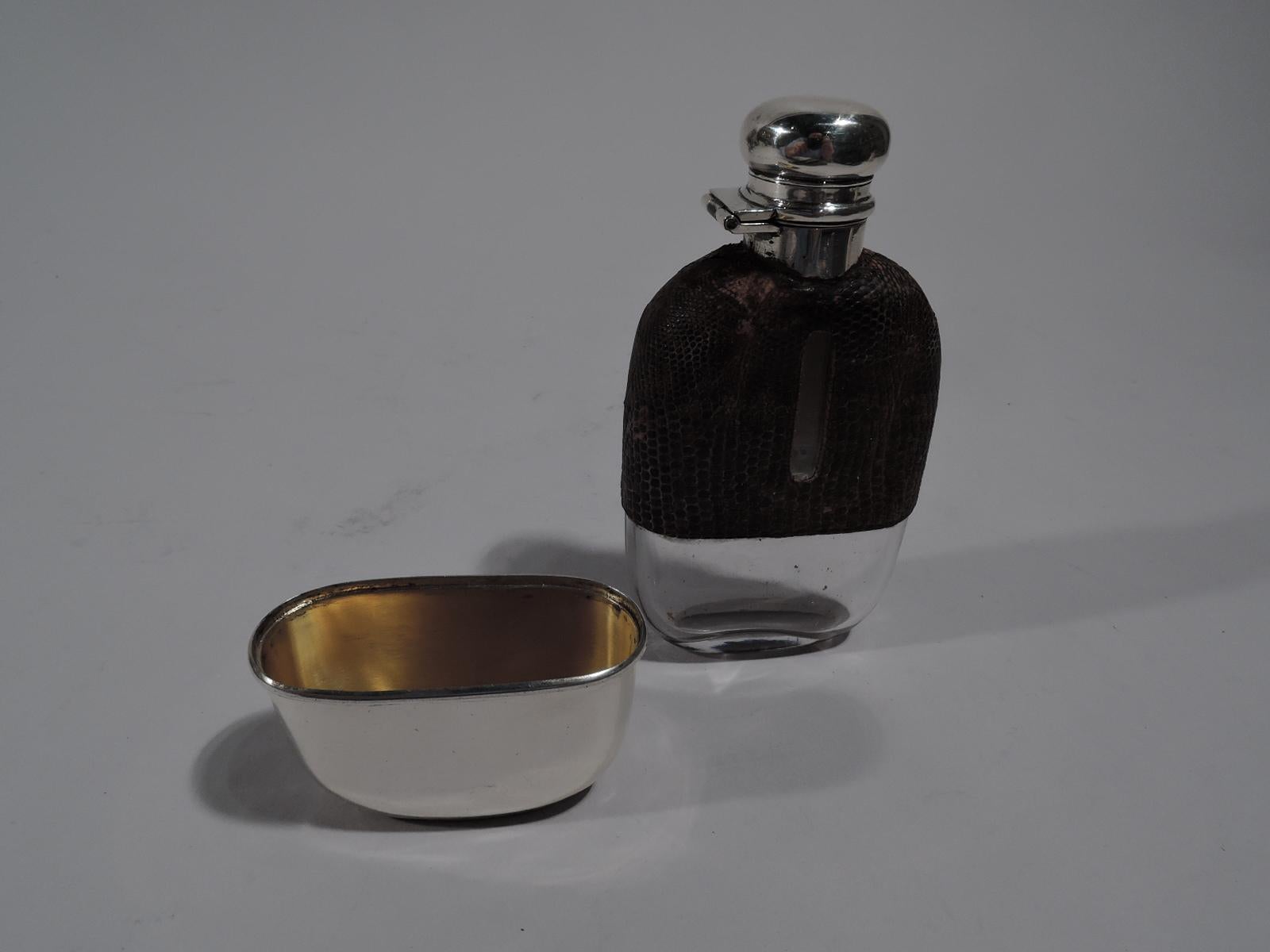 American Edwardian sterling silver safari flask, circa 1910. Clear glass with sterling silver neck and hinged and cork-lined cover. Top half covered with leather. Bottom half has detachable sterling silver cup. Ladies medicinal size. Holds the daily