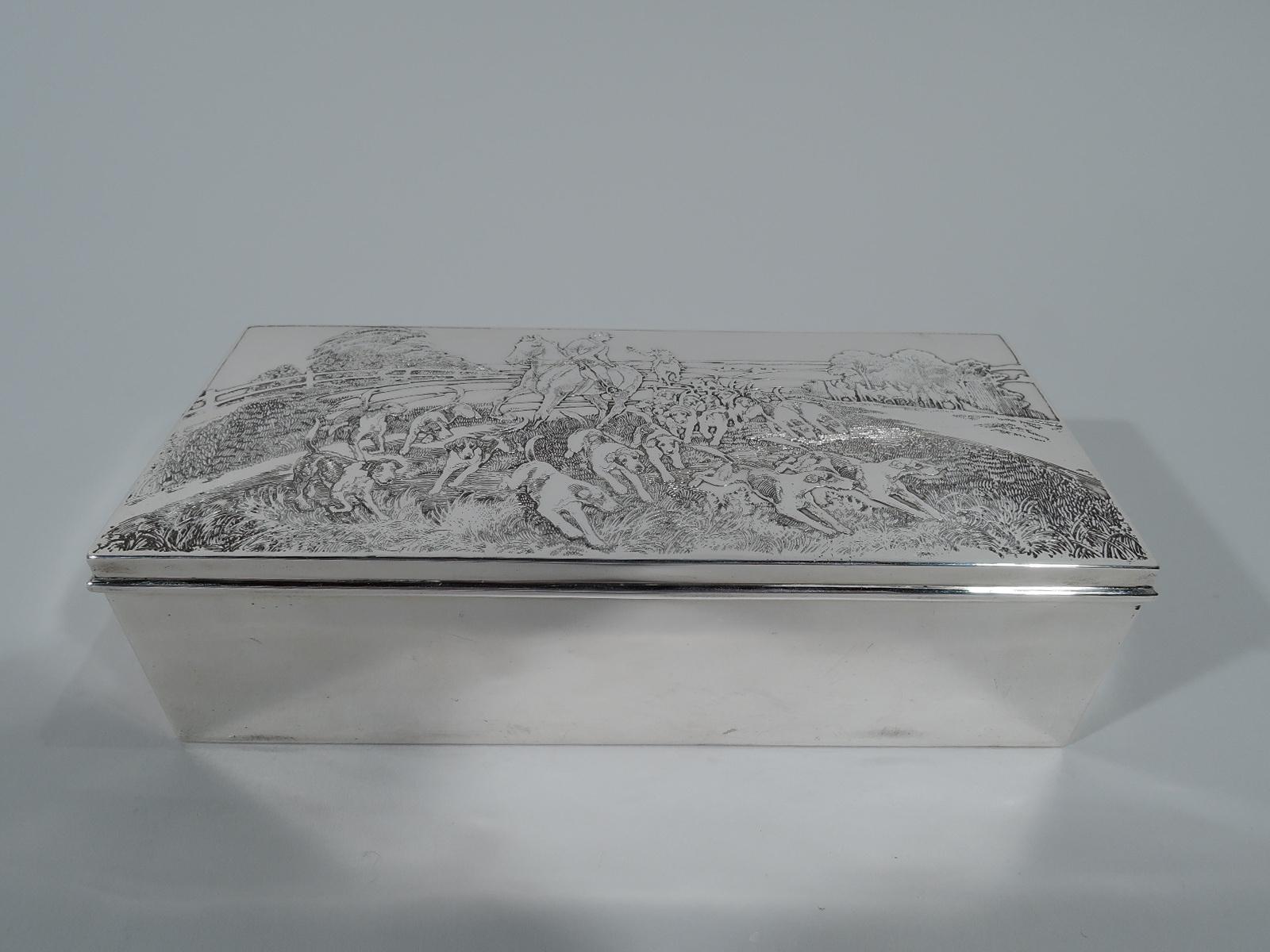 American Edwardian sterling silver box with hunt motif. Rectangular with straight sides and hinged cover. On cover is dense tableaux with hounds in pursuit followed by a mounted hunter who looks back at another wielding a whip. Box interior