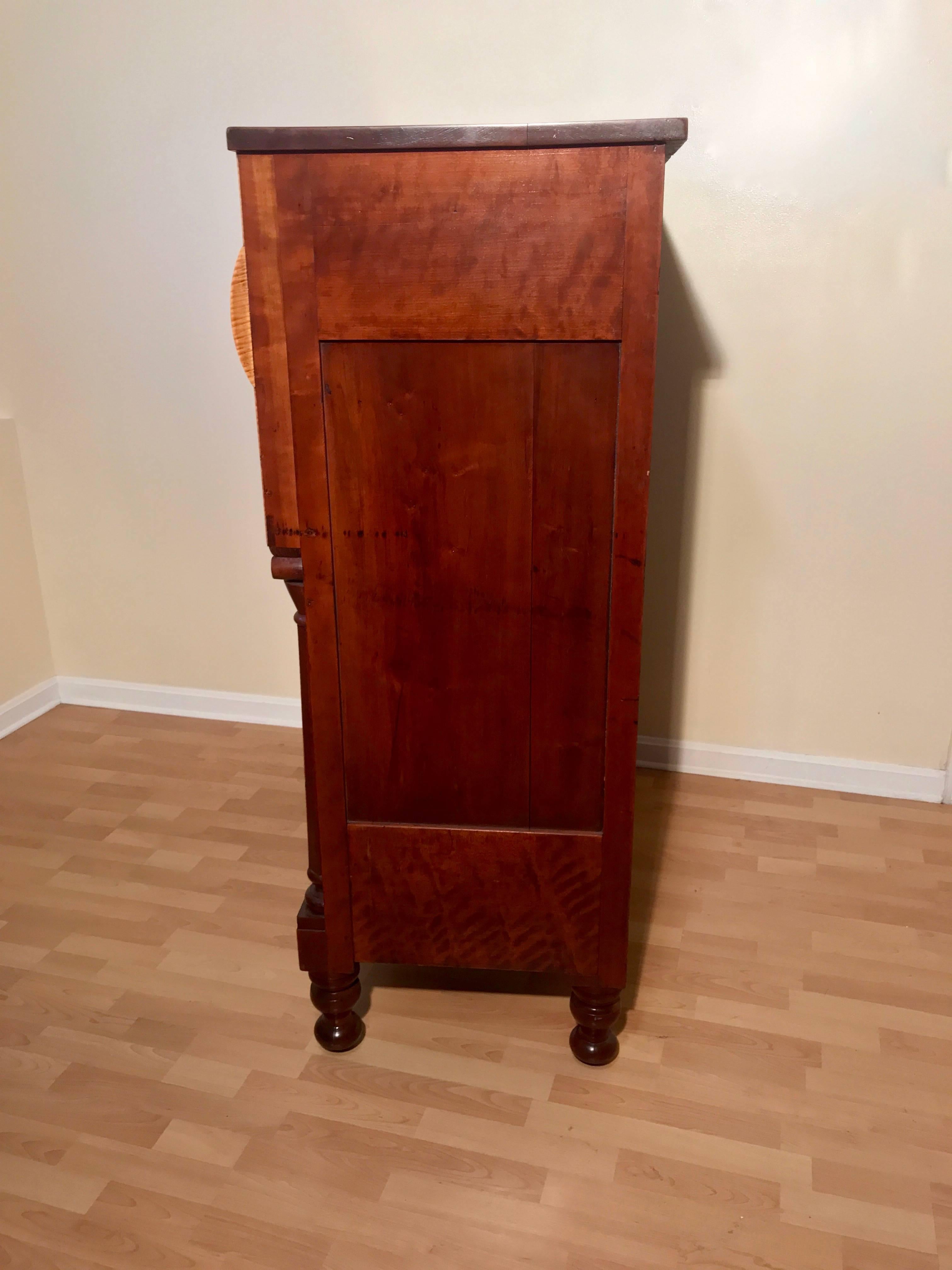 American Empire chest of drawers, circa 1840 in tiger maple and cherry. Turned, planed, carved, veneered (tiger maple) cherry columns over turned feet. Unusual convexed top drawer atop graduated lower drawers. Figured cherry top, hand cut dovetailed