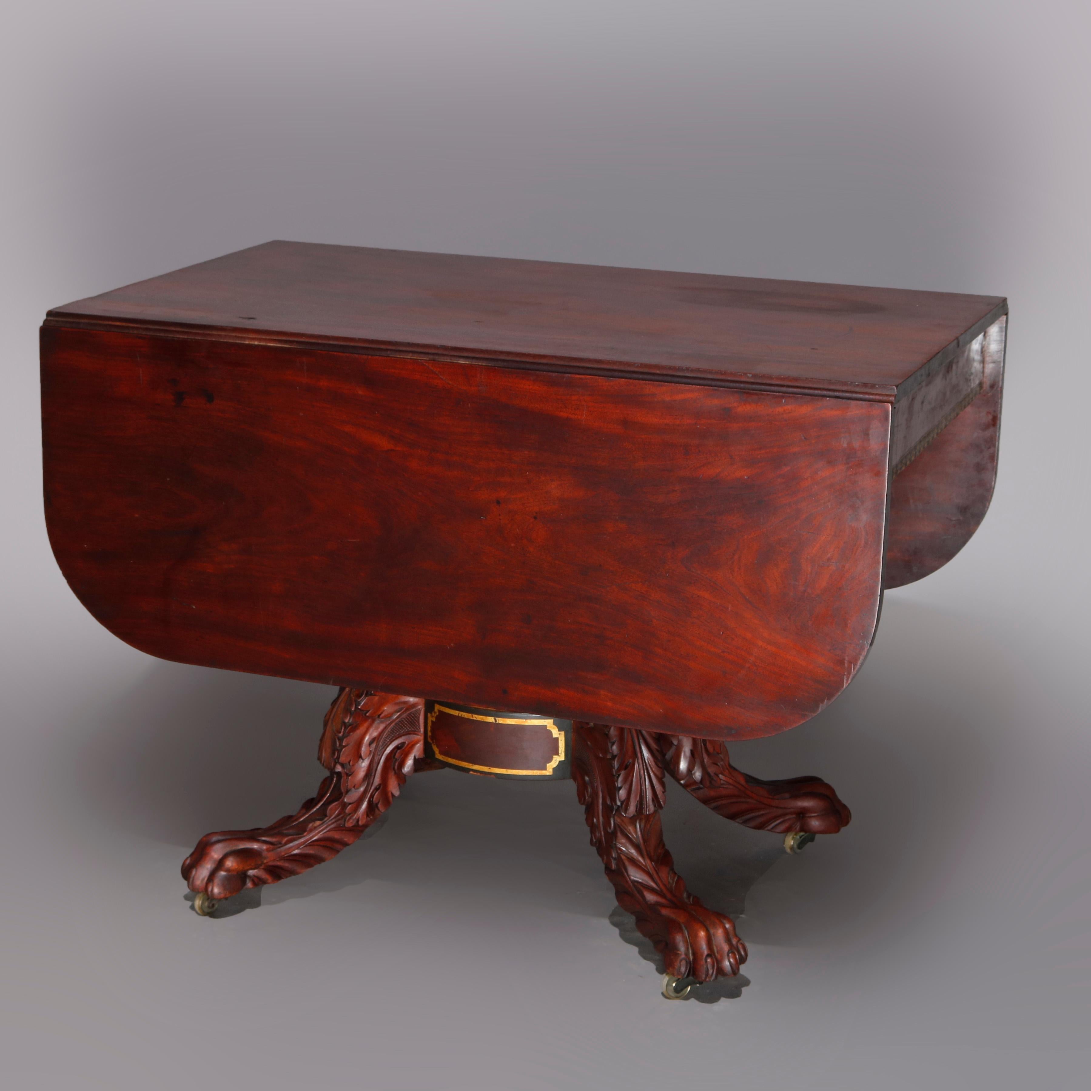 An American Empire Classical drop-leaf table in the manner of Joseph Meeks offers deeply striated flame mahogany construction with single drawer over faceted column base raised on acanthus carved legs terminating in paw feet, gilt stenciling