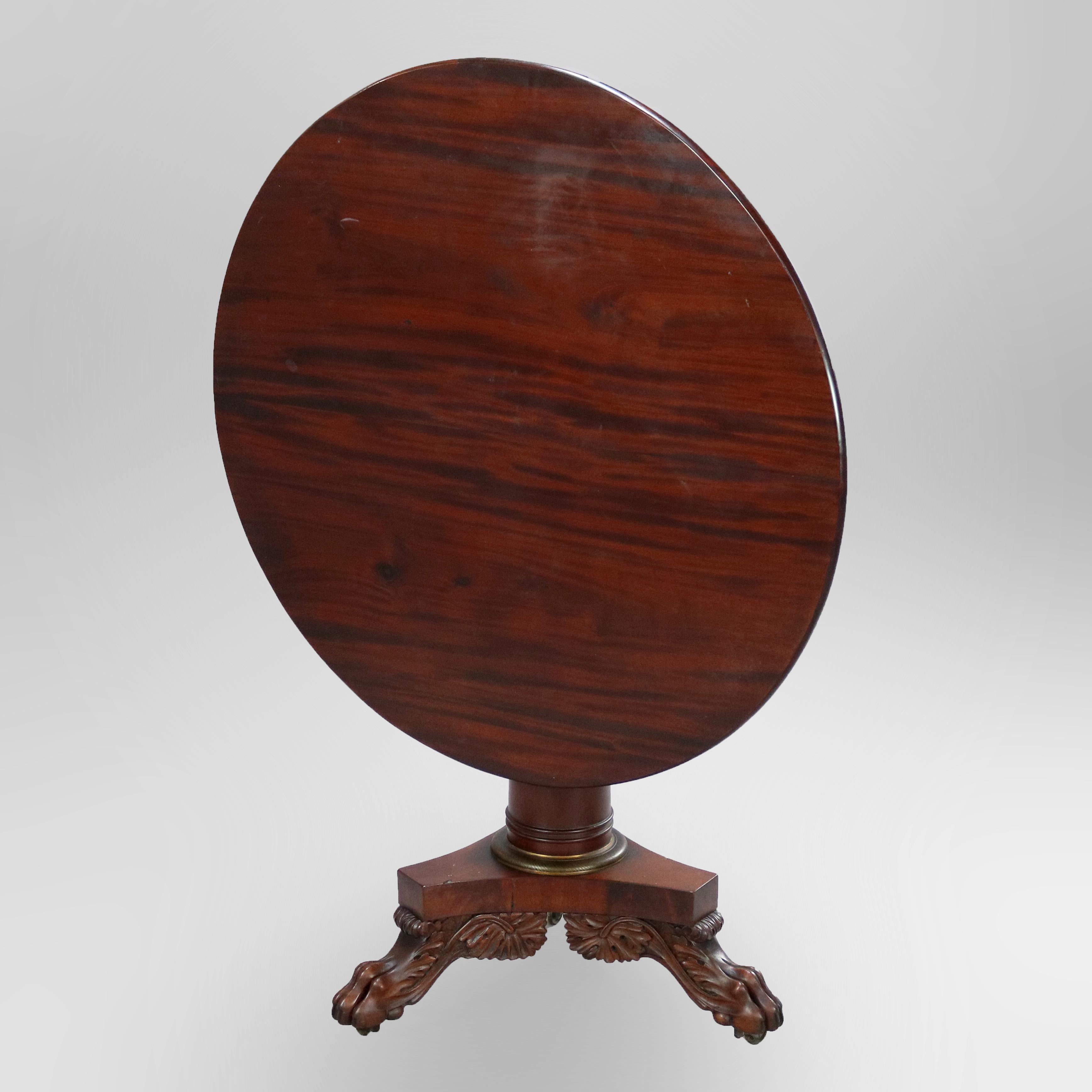 An antique American Empire Classical tilt-top center table in the manner of Anthony Quervelle offers flame mahogany construction with round top over flared central column raised on base with three paw feet, circa 1840.

Measures: 30