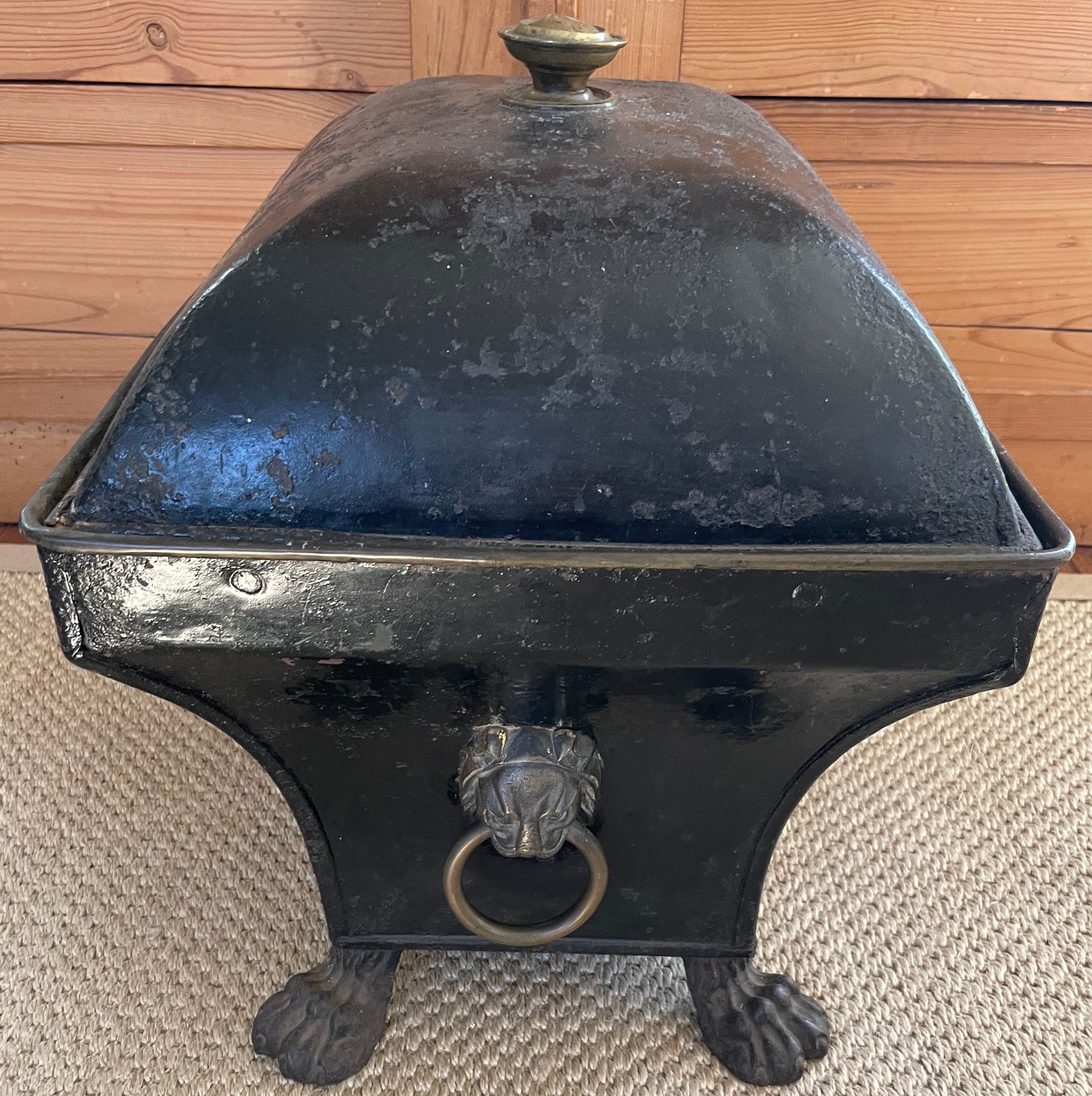 American Empire Black Tole Lion Coal Scuttle Antique sarcophogus-form coal bin/container/cache pot in the American Empire neoclassical
Style with brass finial knopf, lion mask ring handles and paw feet. Wear to bottom commensurate with age and use.