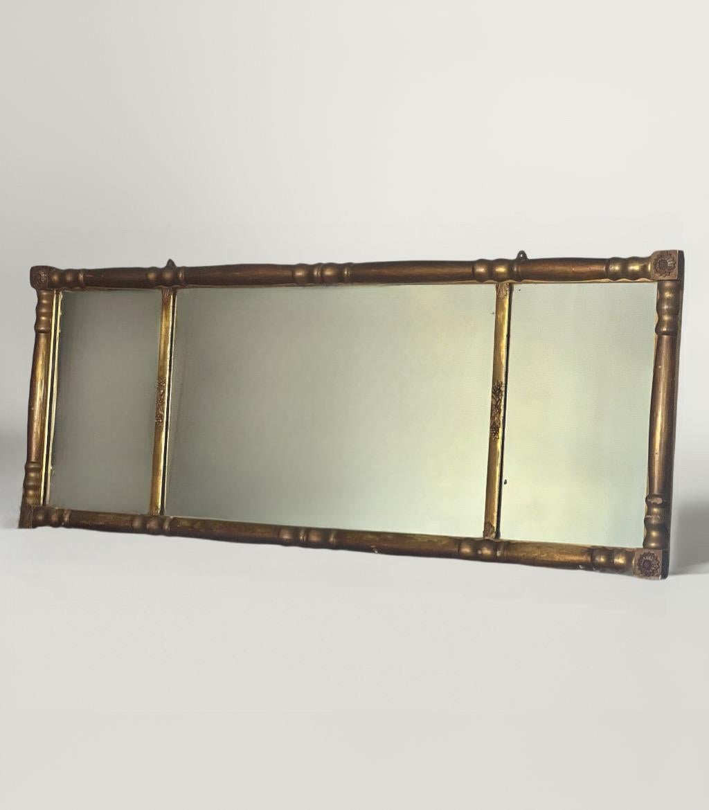 Classically styled 19th century Empire giltwood over mantle three-section wall mirror, circa 1810-1820. It is decorated with carved rosette corners and diminutive floral and acanthus leaf designs. A wonderful antique with a nicely aged patina. It