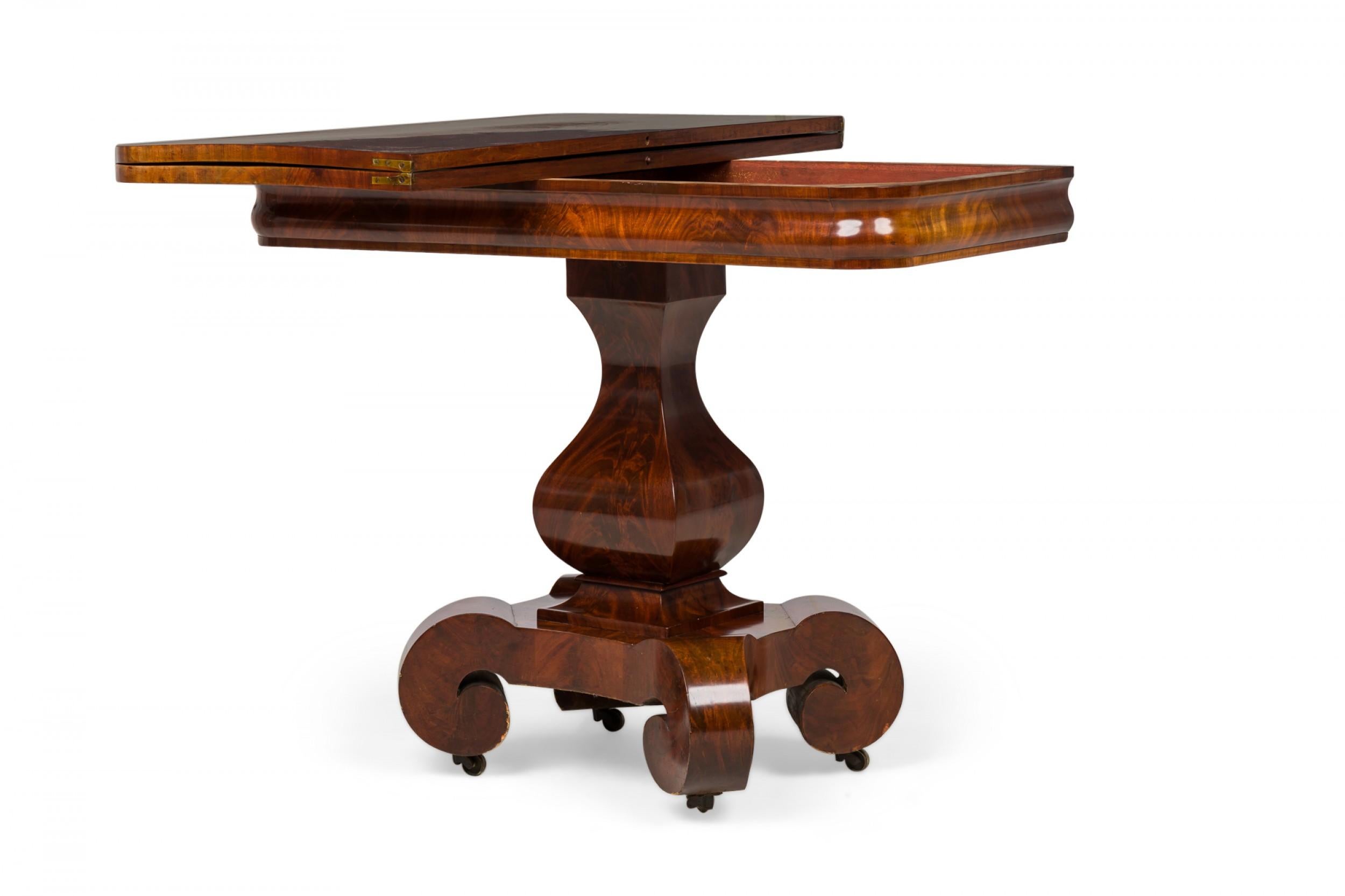 American Empire folding rectangular side table with a sliding table top and extendable hinged leaf, resting on a baluster pedestal base ending in 4 flattened scroll legs with casters, finished in a mahogany veneer.