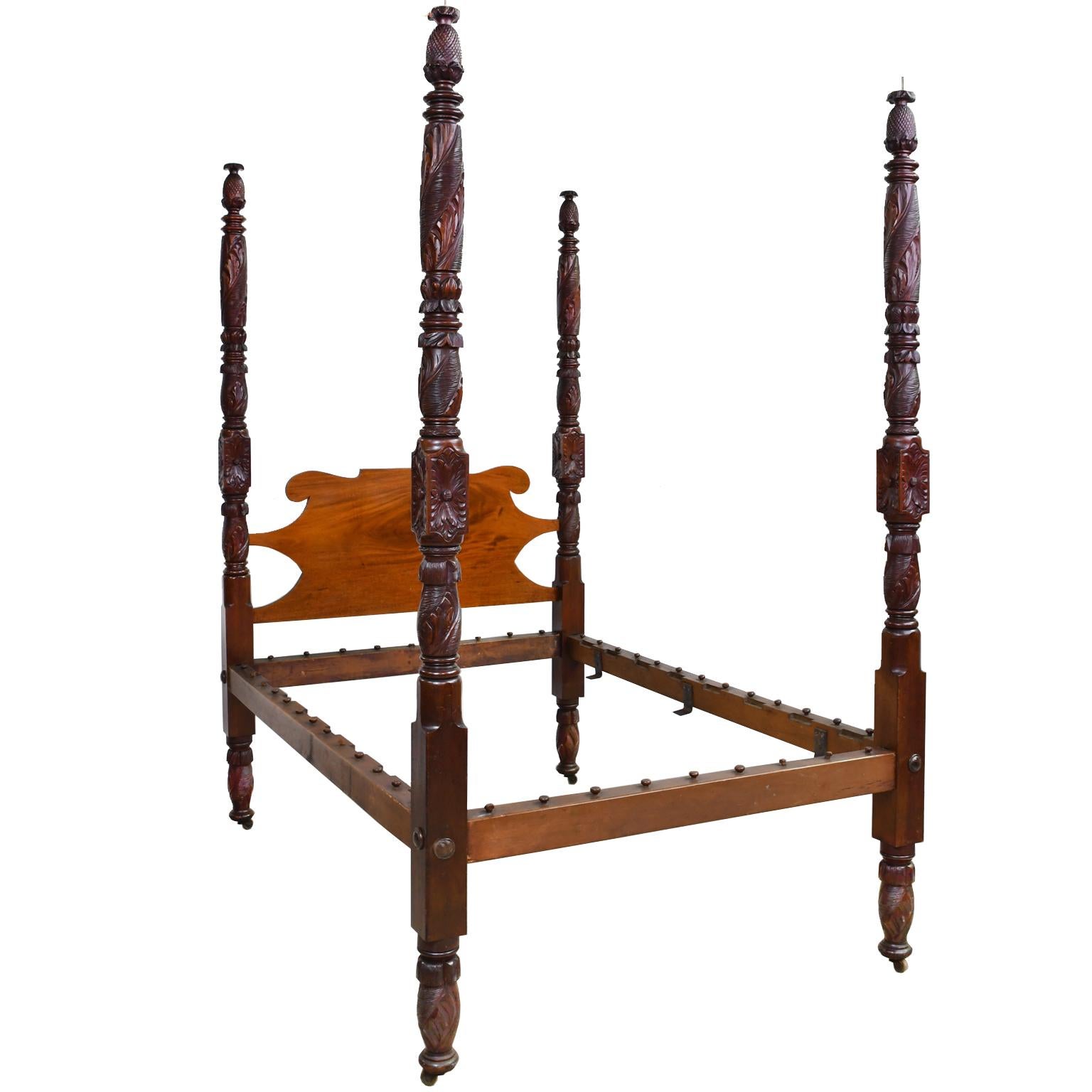 A very finely carved American Empire four poster bed. At the top of each post is a carved pineapple, the emblem of hospitality, and under these are ringed turnings followed by round turnings with acanthus carvings, and carved blocks with rosettes,