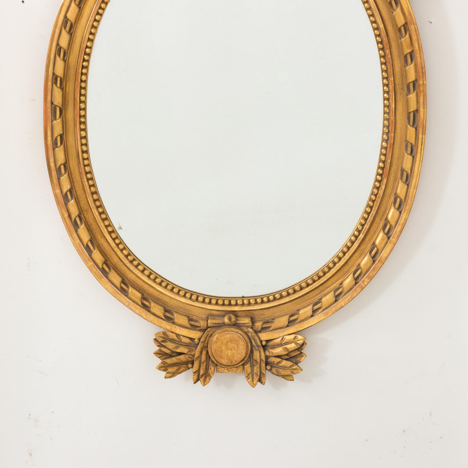 American Empire style gilded mirror with beaded trim, circa 1890. The crown also features carved bow-knot ribbons with flowers and a base with wheat-sheaf motifs.
 
