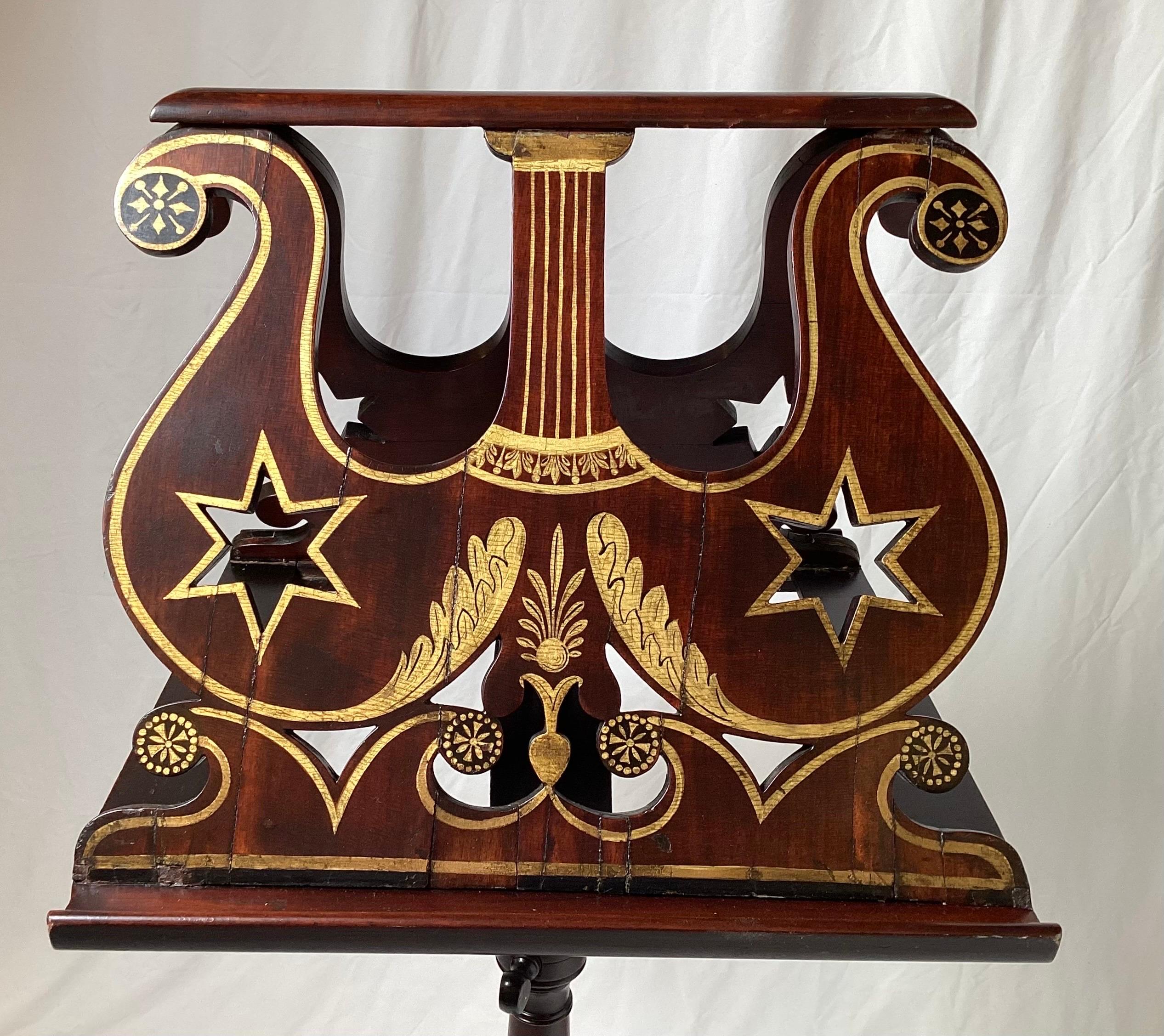 Am American Empire solid mahogany hand carved adjustable music stand with hand painted gilt decoration/ The graceful double sided stand with elaborate gold decoration on an adjustable center column resting on three hand carved empire legs. adjusts