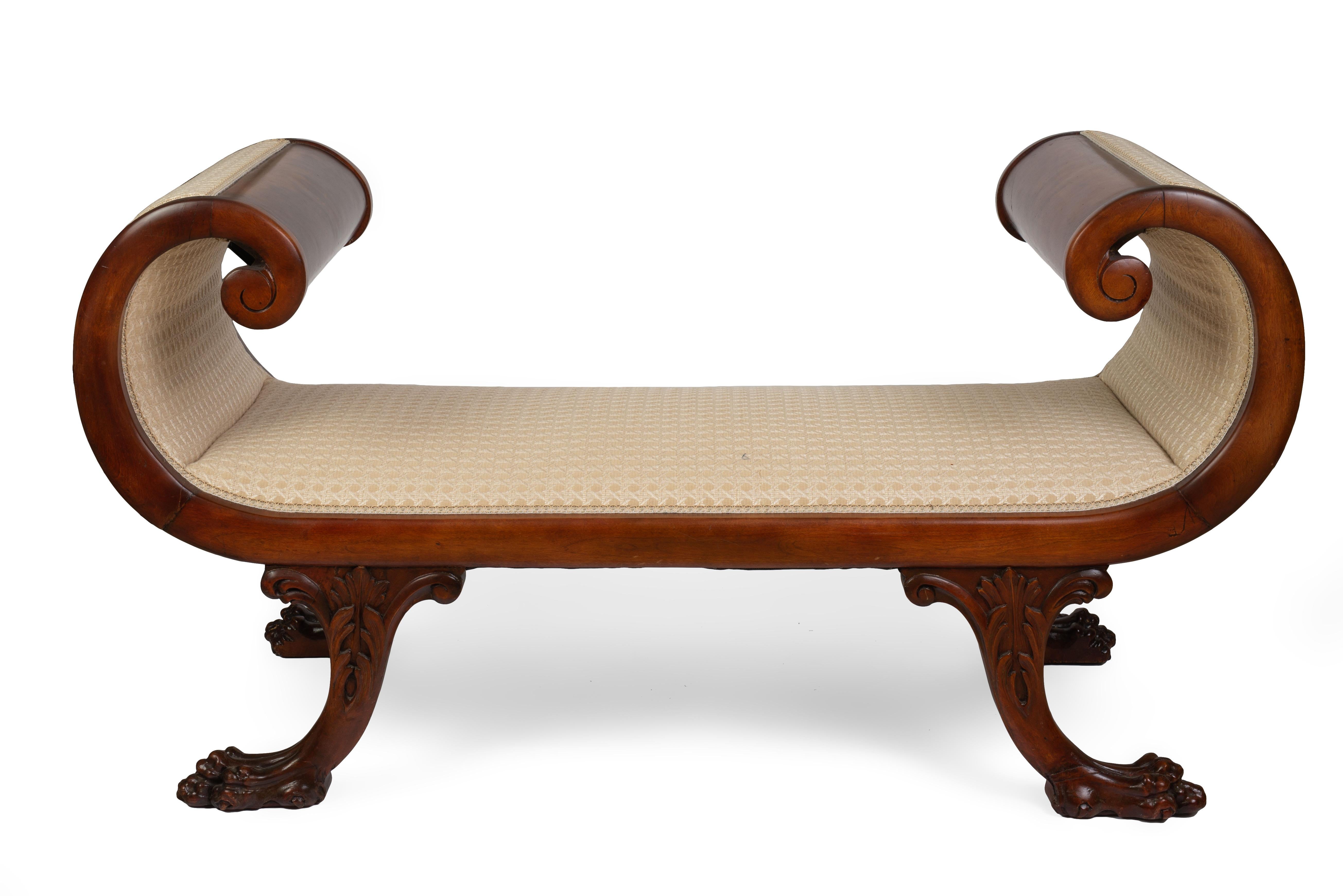 The rectangular seat and scrolled arms upholstered, raised on splayed foliate carved legs ending in paw feet.