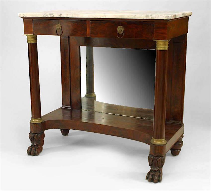 American Empire mahogany console table with mirror back and column sides supported by claw feet with 2 drawers have bronze lion head pulls and trim with a white marble top.
