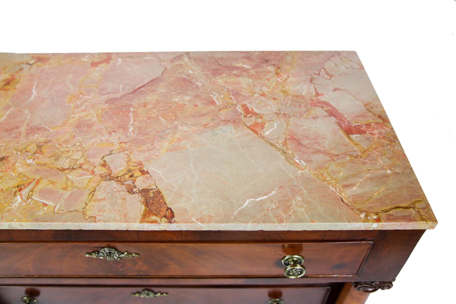 American Empire mahogany marble-top chest, with rojo Alicante marble top, the four drawers with crotch mahogany veneer, brass knobs and escutcheons, tiger birch columns above tapered front feet, turned back feet, inset panel sides.