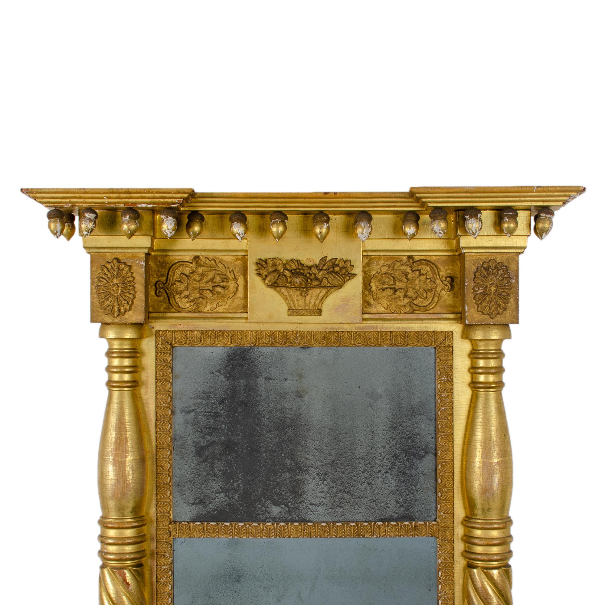 An early Empire giltwood pier mirror with rope twist split column, flower basket and leaf blocks with acorn spherules and original mercury glass, c.1815-1840.
 
29 inches wide by 5 ¼ inches deep by 48 ½ inches tall