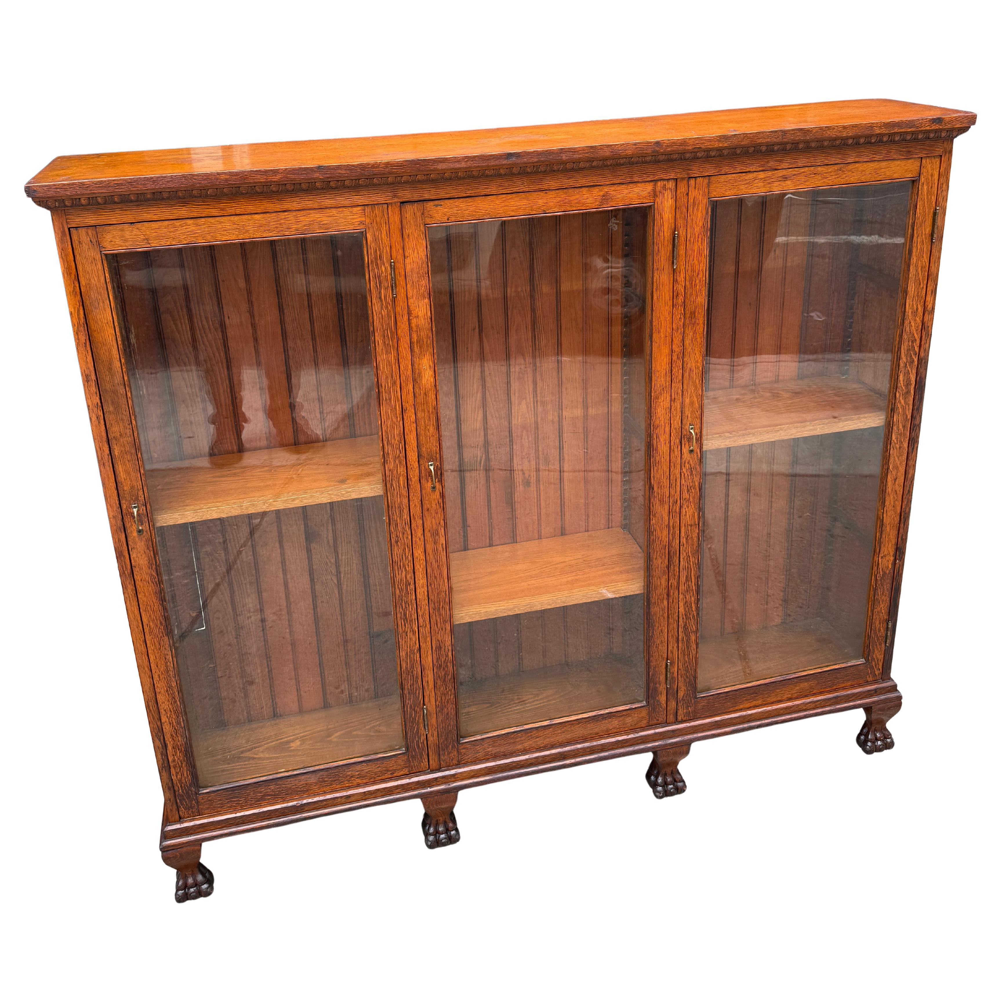 Un eccezionale mobile libreria triplo stretto in stile Impero Revival e Arts & Crafts americano, circa 1900. Realizzato con maestria in quercia a quarto d'altezza riccamente figurata, il mobile mostra gli audaci raggi midollari e le venature