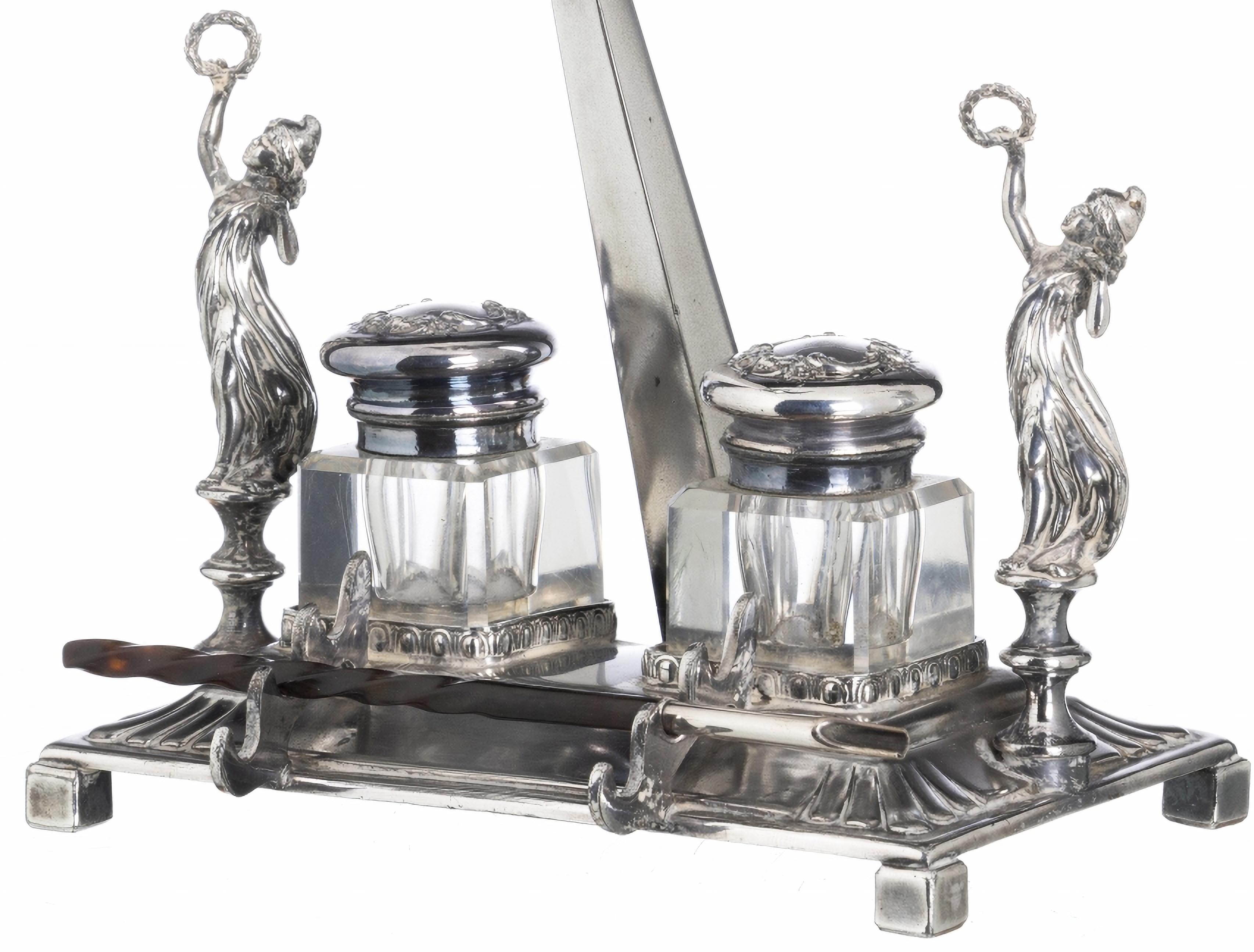 DESKTOP ENKWELL AMÉRICAIN EMPIRE STYLE

Début du 20e siècle
en métal argenté, marque sur la base de l'orfèvre 'Reed & Barton' du Massachusetts, datée de 1824-1928,
décoré d'un aigle royal et de deux figures féminines.
Cartouches d'encre avec