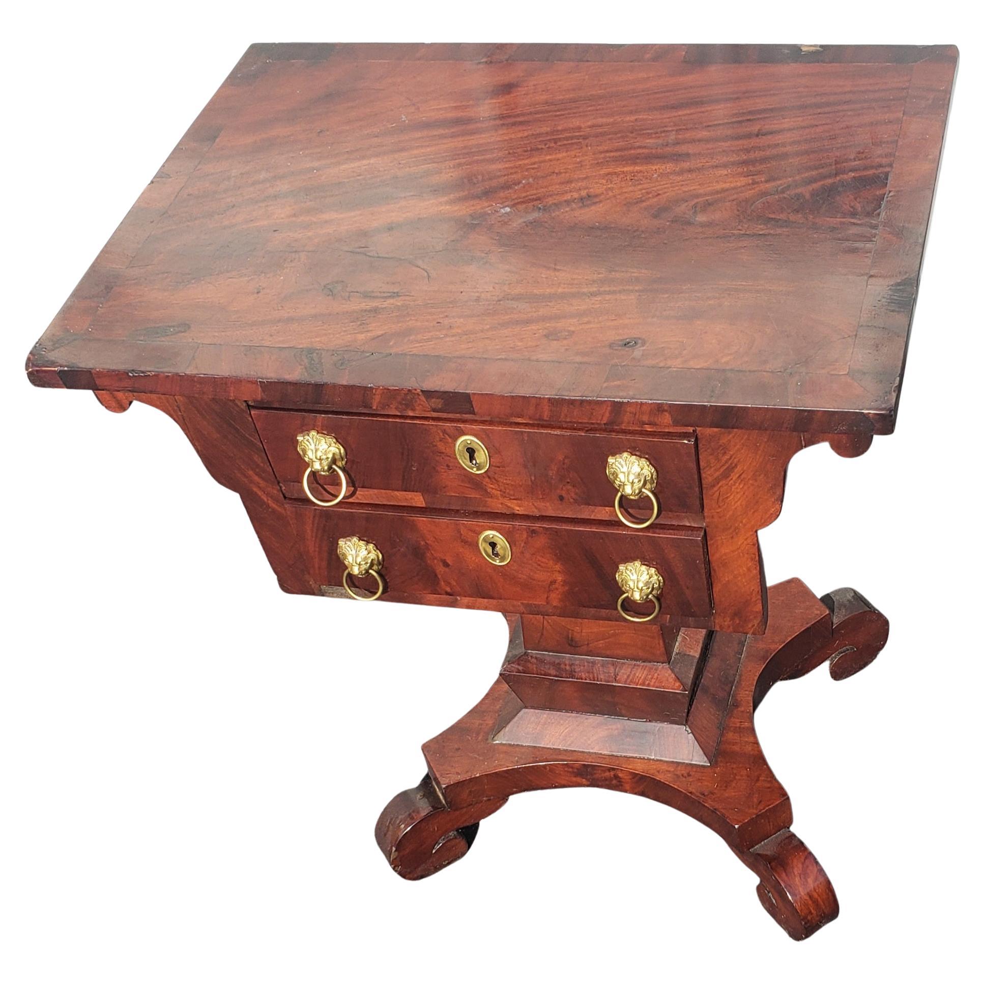 Late 1800s flame mahogany American Empire side table, parlor table, end table. Two functional dovetail drawers. Drop down lion head pulls. Good vintage condition with wear appropriate with age and use.
Measures 22