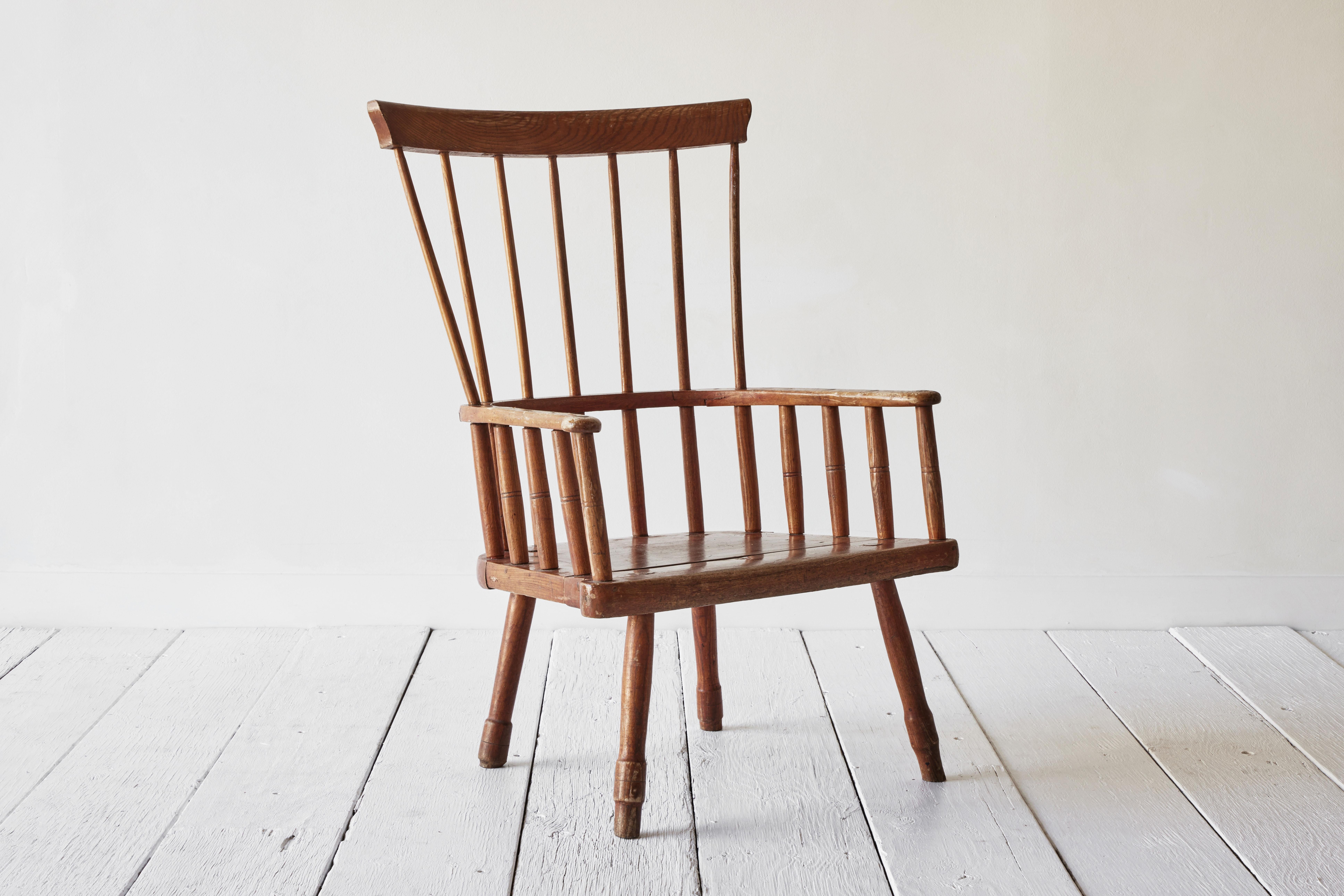 This classic American fan-back Windsor chair features a bentwood back, splayed legs pegged directly into the seat, armrests that extend around the chair and a spindle back. All of these attributes are characteristic of Windsor chairs which