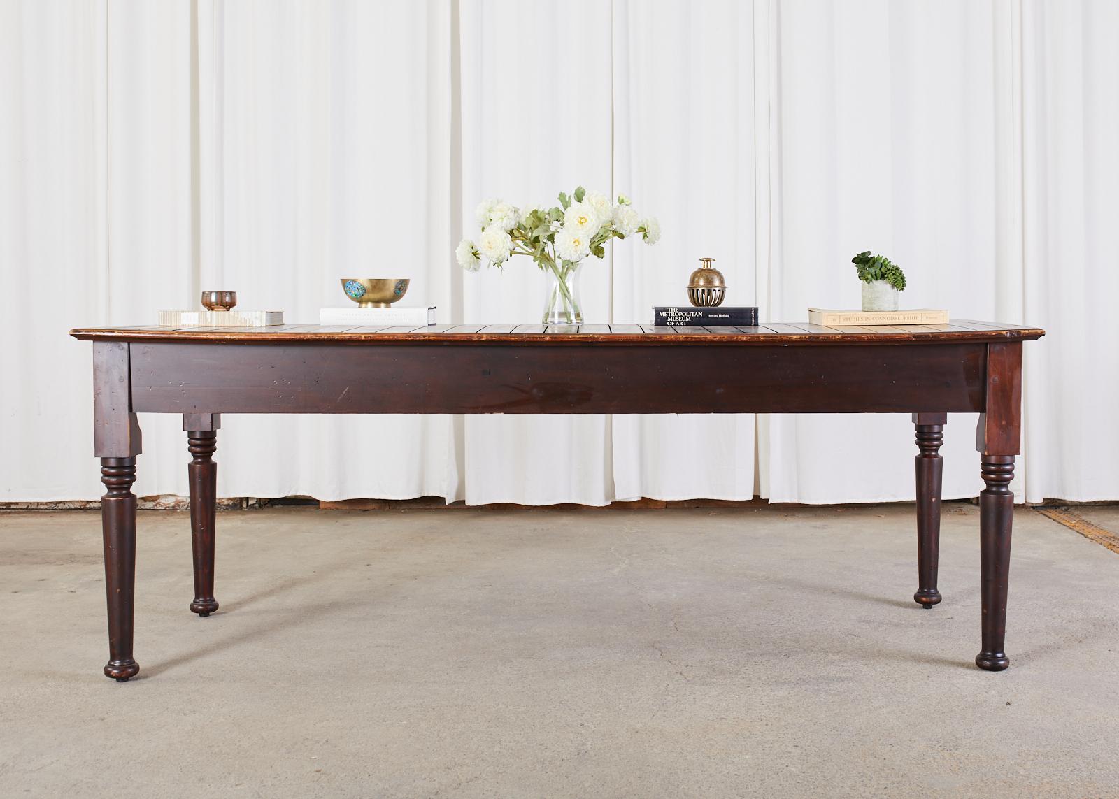Bespoke American farmhouse work table, display table, dining table or console made by Crow Works for Abercrombie and Fitch. The large table features a plank top with a framed edge. The top is supported by thick, turned legs ending with round feet.