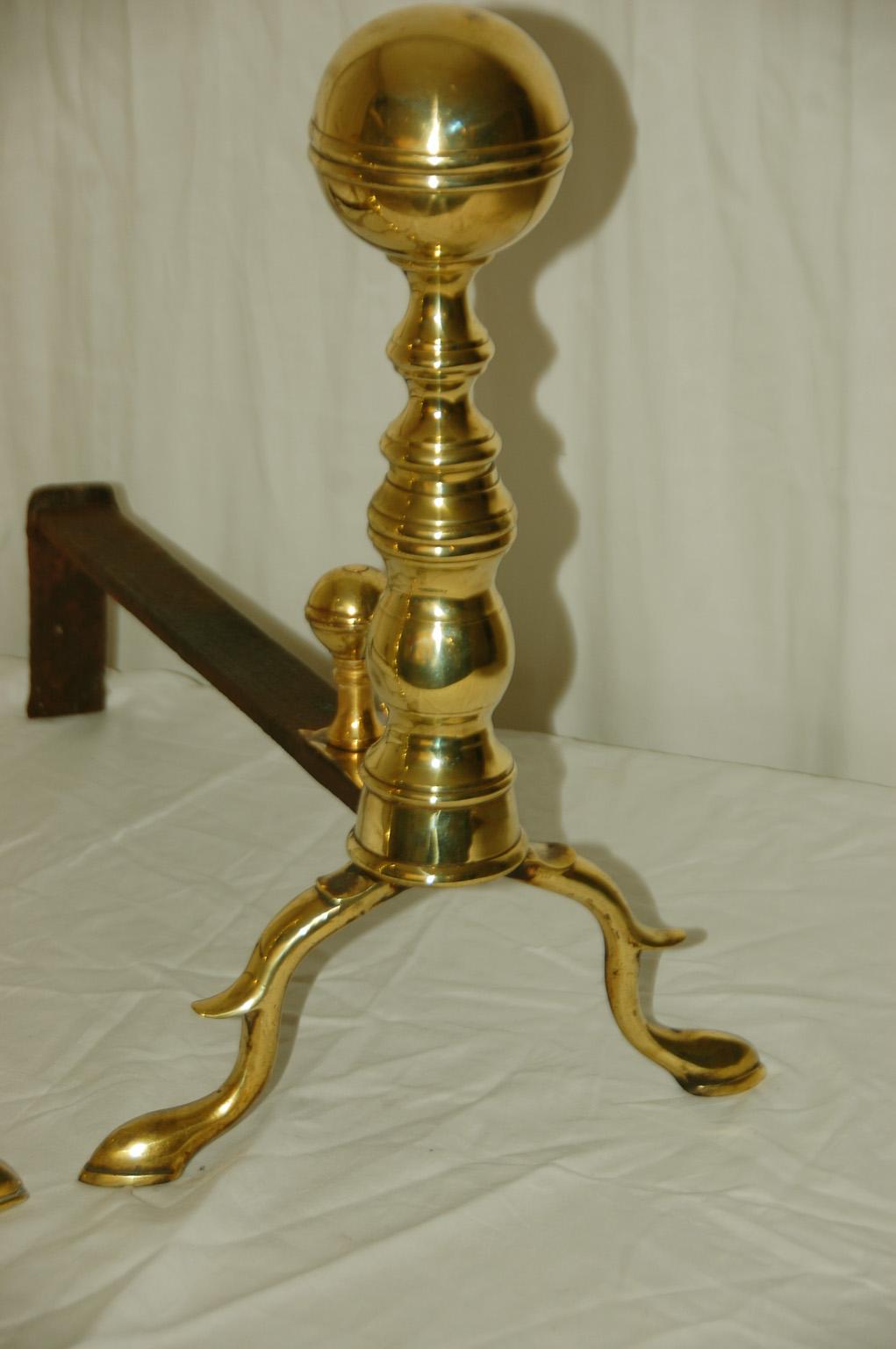 American Federal period cast brass belted ball top pair of andirons. These 15 inch high andirons have their original belted ball log stops but they have had new bolts added to secure them (only visible when you turn the andirons upside down). They