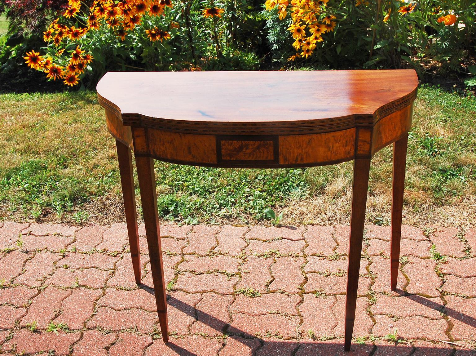 American Federal period serpentine mahogany foldover tea or cardtable. This elegantly shaped table has serpentine sides, leading to a gently bowfront front, the slim tapered legs have an inlaid cuff which marks the change of angle to a sharply