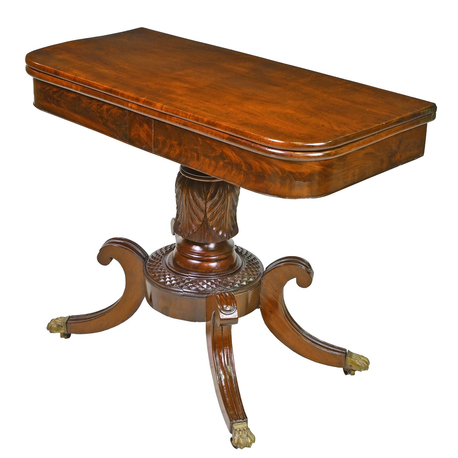 A lovely Federal card table in fine mahogany with hinged rectangular top pivoting and opening to a square supported by a turned column with tobacco leaf carvings over a round base with carved knurling reminiscent of pineapples. Four 