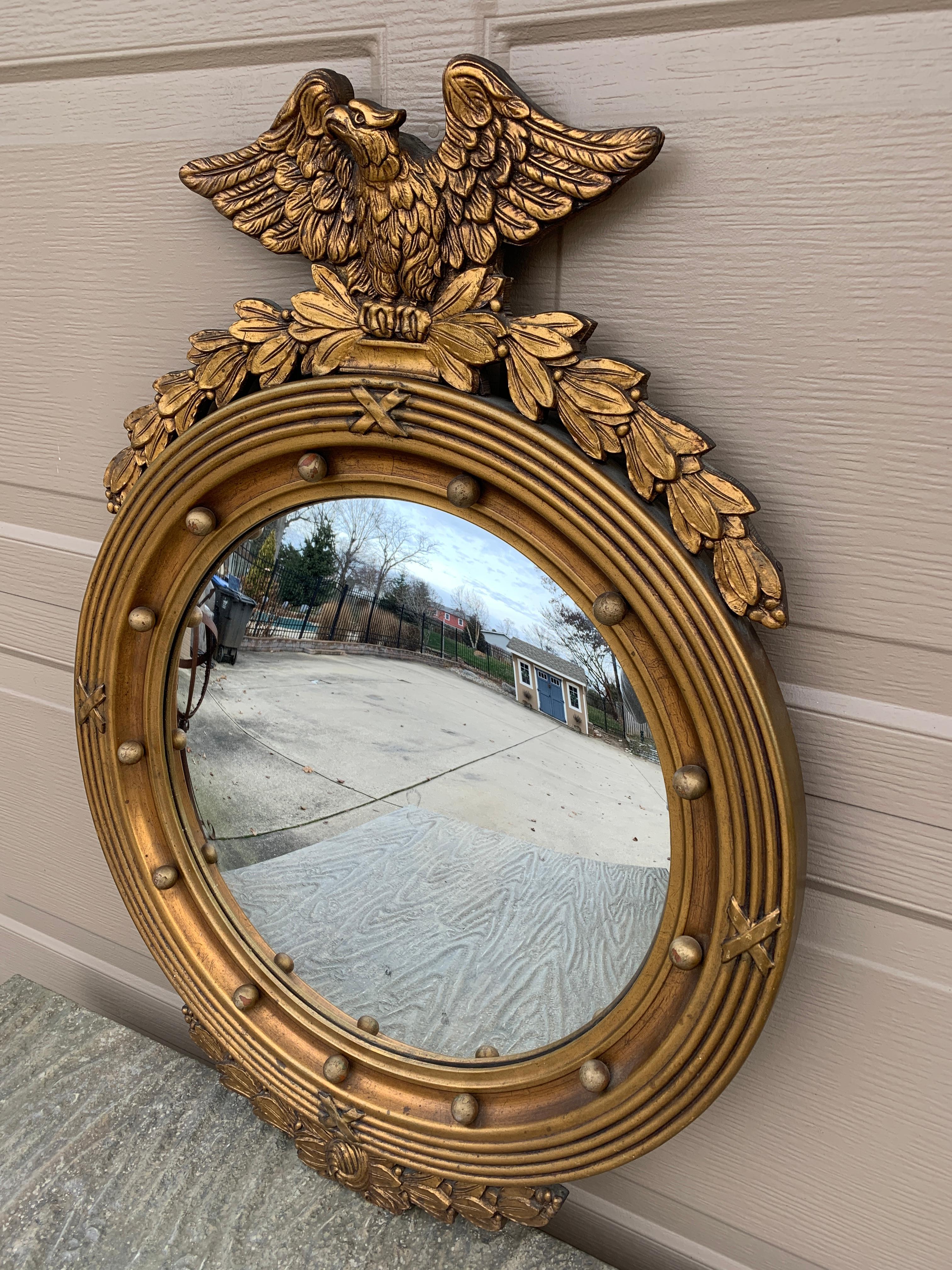 A gorgeous Federal or Regency style convex bullseye wall mirror featuring a carved eagle with open wings standing on olive branches and 13 small spheres representing the original 13 colonies around the inside perimeter.

USA, Mid-20th