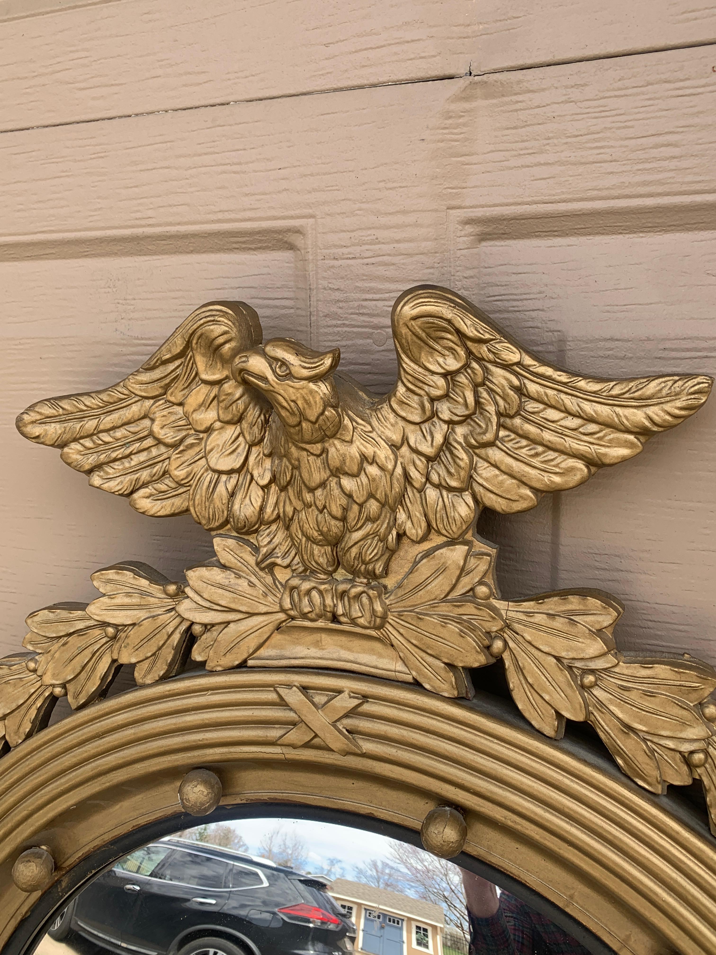 A gorgeous Federal or Regency style convex bullseye wall mirror featuring a carved eagle with open wings standing on olive branches and 13 small spheres representing the original 13 colonies around the inside perimeter.

USA, Mid-20th