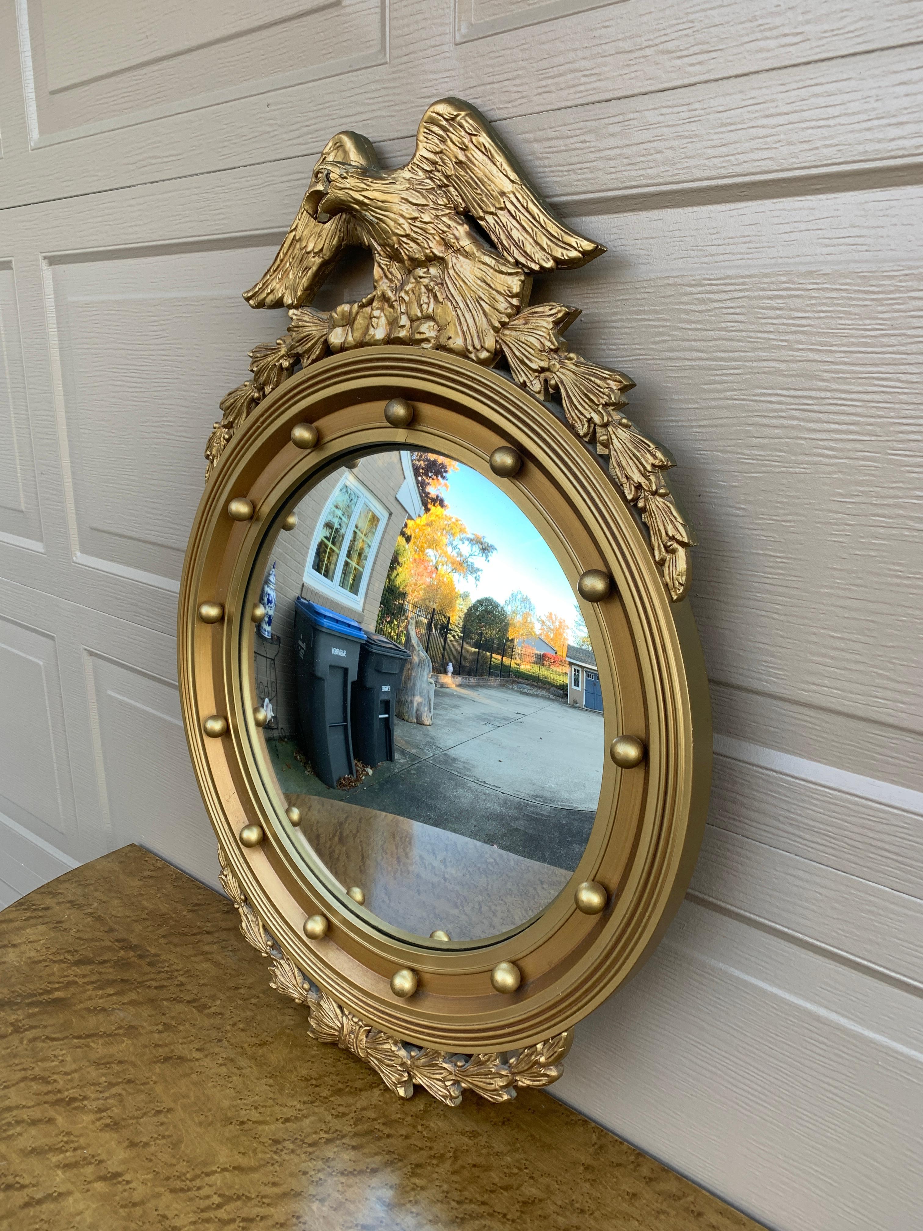 A gorgeous Federal or Regency style convex bullseye wall mirror featuring a carved eagle with open wings standing on olive branches and 13 small spheres representing the original 13 colonies around the inside perimeter.

USA, Mid-20th