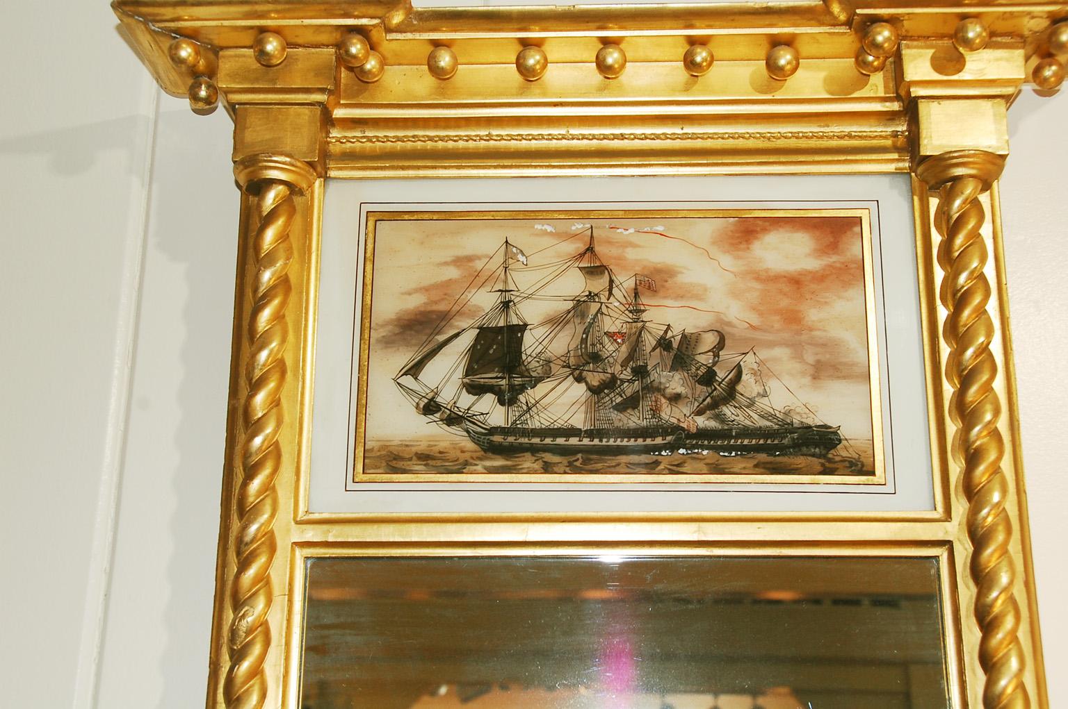 American Federal period gold leaf mirror with beautifully carved rope columns, eglomise panel and deep cornice with pendant balls. The reverse painting on glass depicts a battle between an American ship of the line and a British ship of the line,