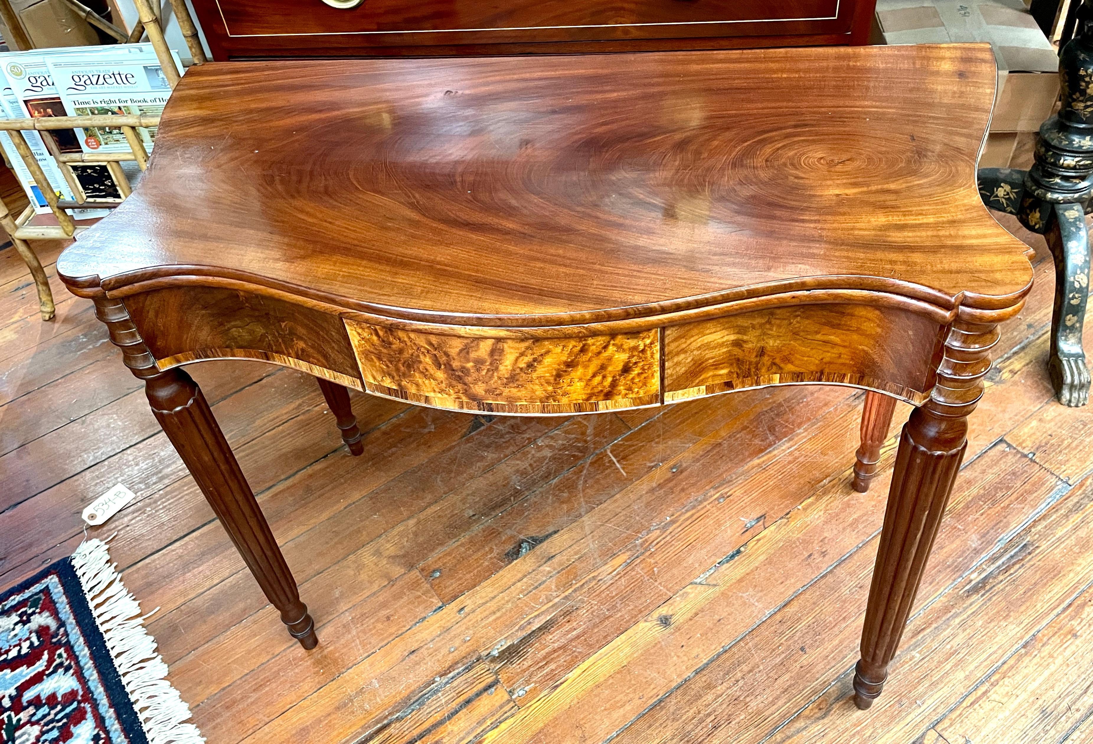 Exceptional quality antique American (likely Boston or North Shore of Massachusetts) inlaid figured mahogany Sheraton style serpentine flap-top games table with rosewood crossbanding and a central panel of highly figured satin birch.

This