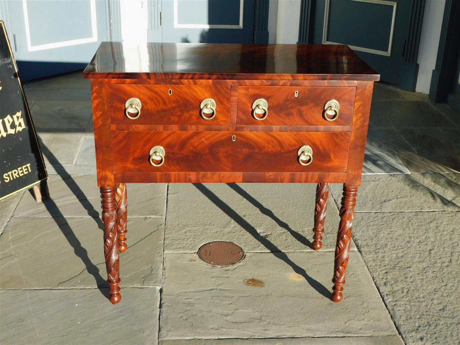 American Federal mahogany three drawer server with a carved figured molded edge top, original circular brasses, and resting on carved acanthus turned ringed legs with ball feet. Secondary wood consist of Tulip Poplar. Boston, MA early 19th century.