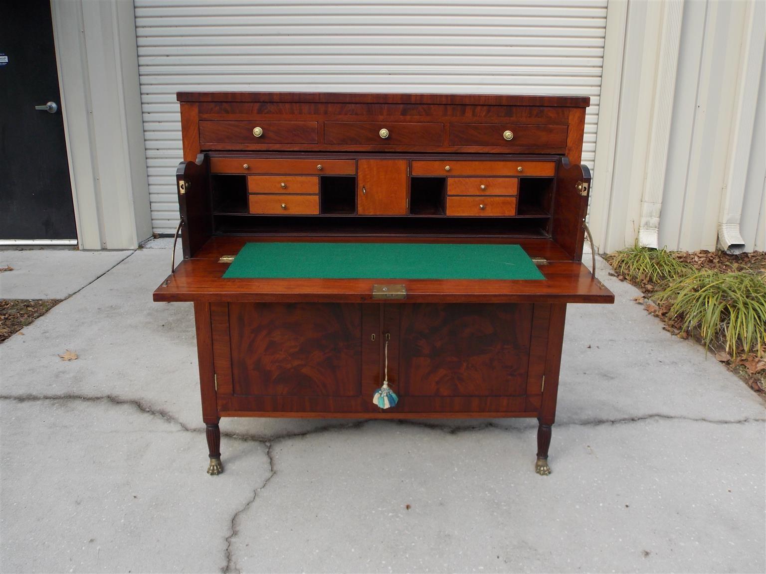 American Federal mahogany butler's desk with a carved molded edge, three upper drawers with original brass knobs, sliding fall front interior desk with Satinwood drawers and pigeon holes, baize writing surface, two lower book matched mahogany
