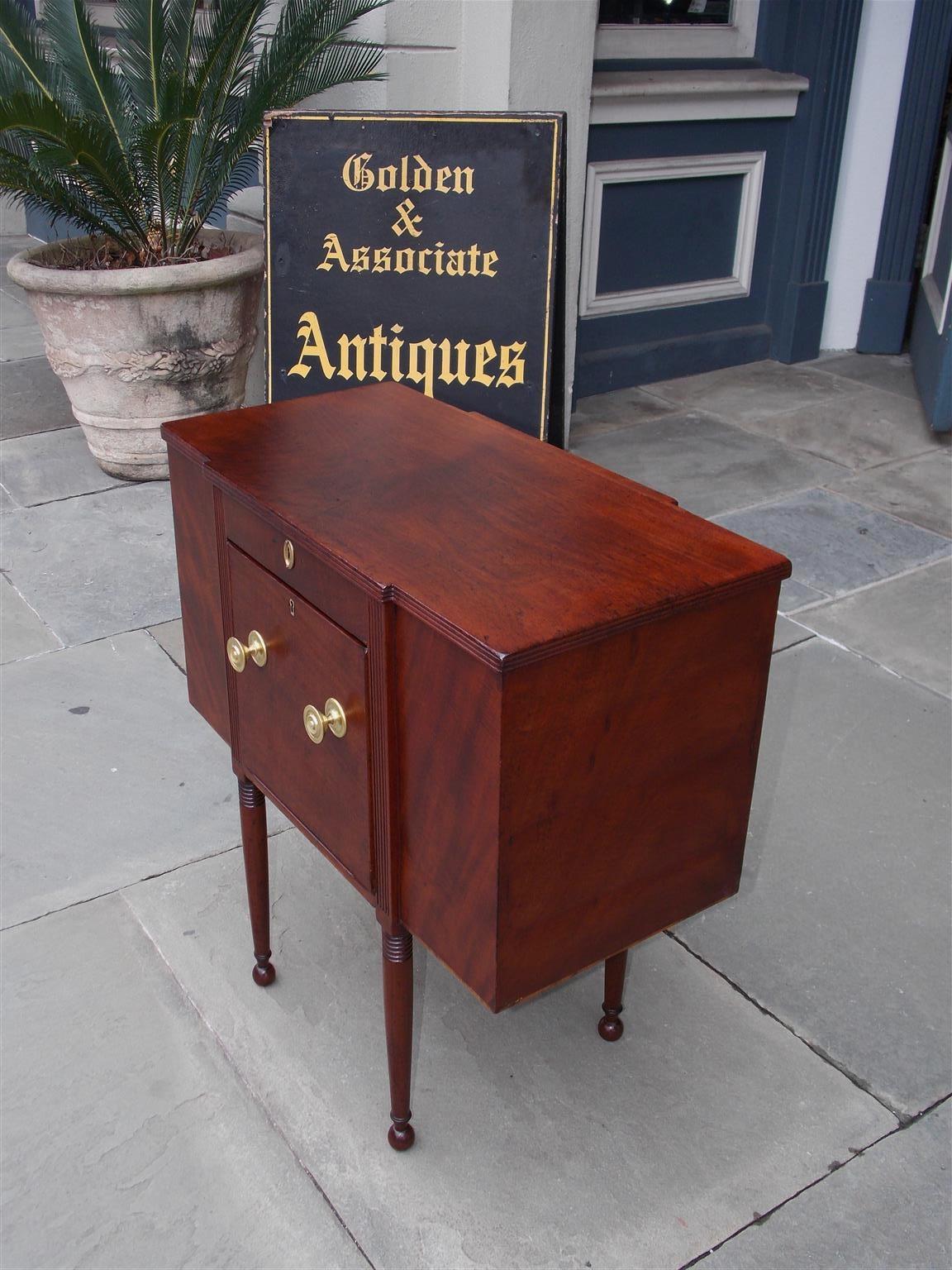 American Federal mahogany work table with a hinged top revealing two flanking compartments, deep centered reeded front drawer with original brasses, and terminating on turned tapered ringed legs with ball feet. Secondary wood consist of white pine