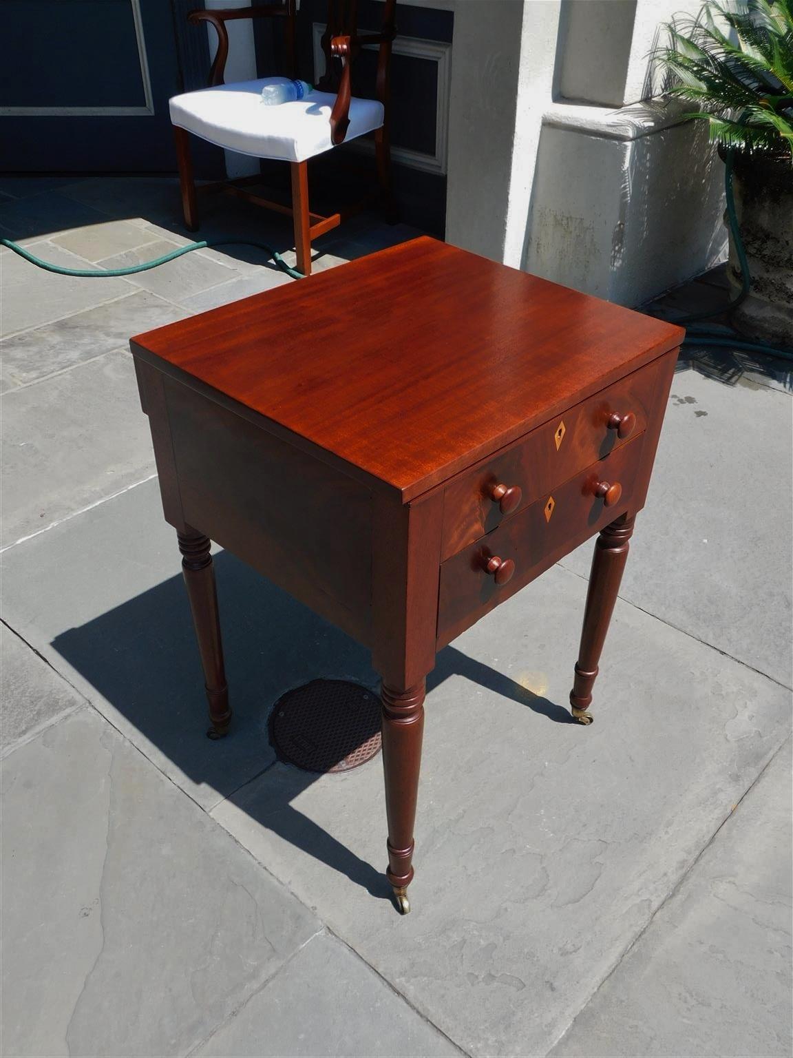 American Federal Mahogany one drawer side table with fitted interior desk, walnut diamond escutcheons, original four wooden knobs, and resting on turned bulbous ringed legs with the original brass casters. Secondary wood consist of white pine and