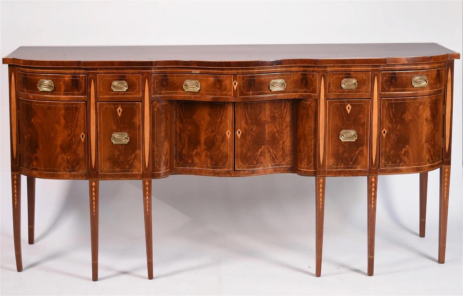 Antique Mahogany Hepplewhite Baltimore Federal Serpentine Front Sideboard, with oval and bellflower inlay, the front facade has four drawers over two central doors flanked by two bottle drawers and another bowed doors. 

A Fine American Period
