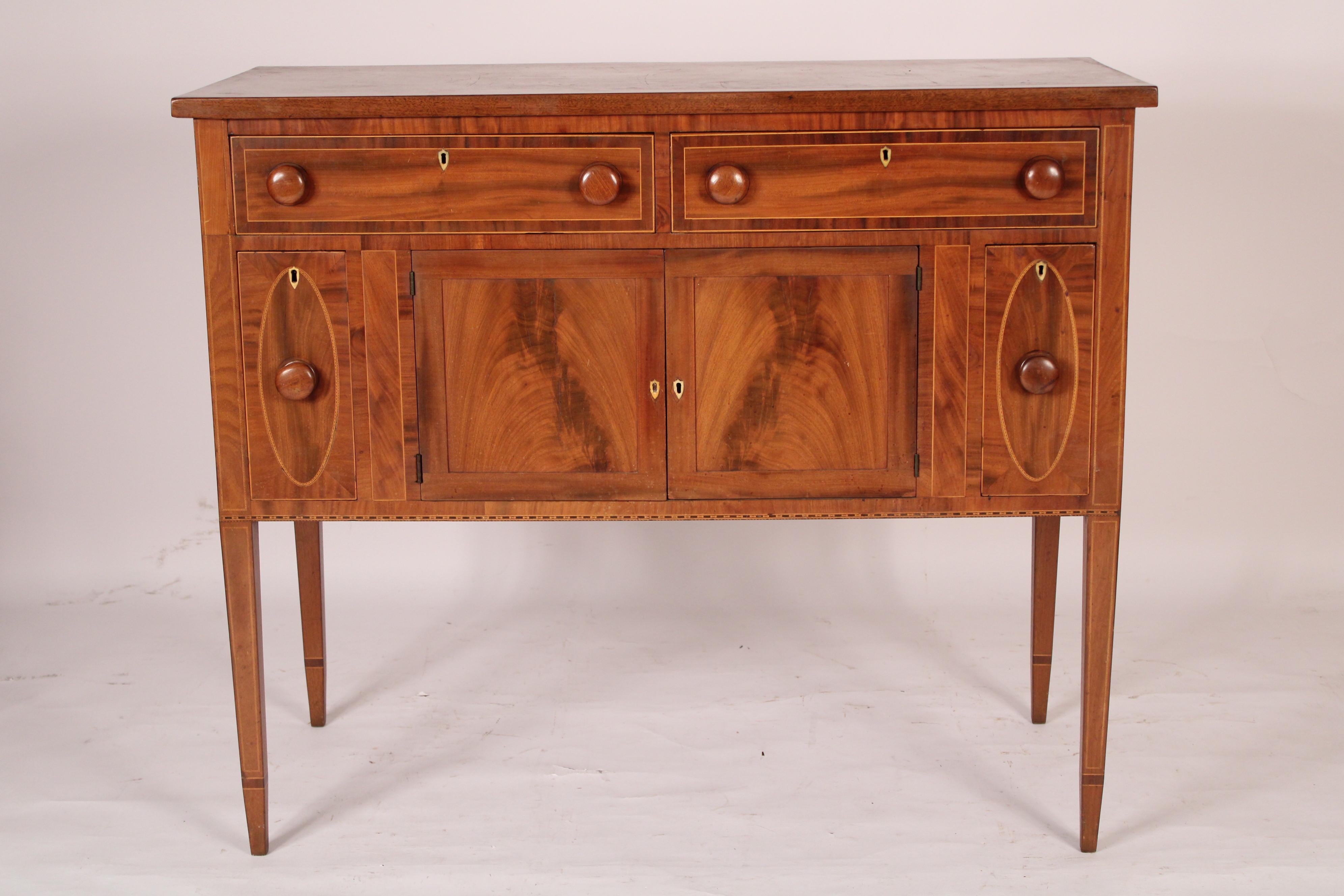 American Federal flame mahogany and elm sideboard, early 19th century. With an overhanging elm top over two mahogany drawers with mahogany crossbanding, wood knobs and bone shield shaped escutcheons, below are two small flame mahogany drawers with
