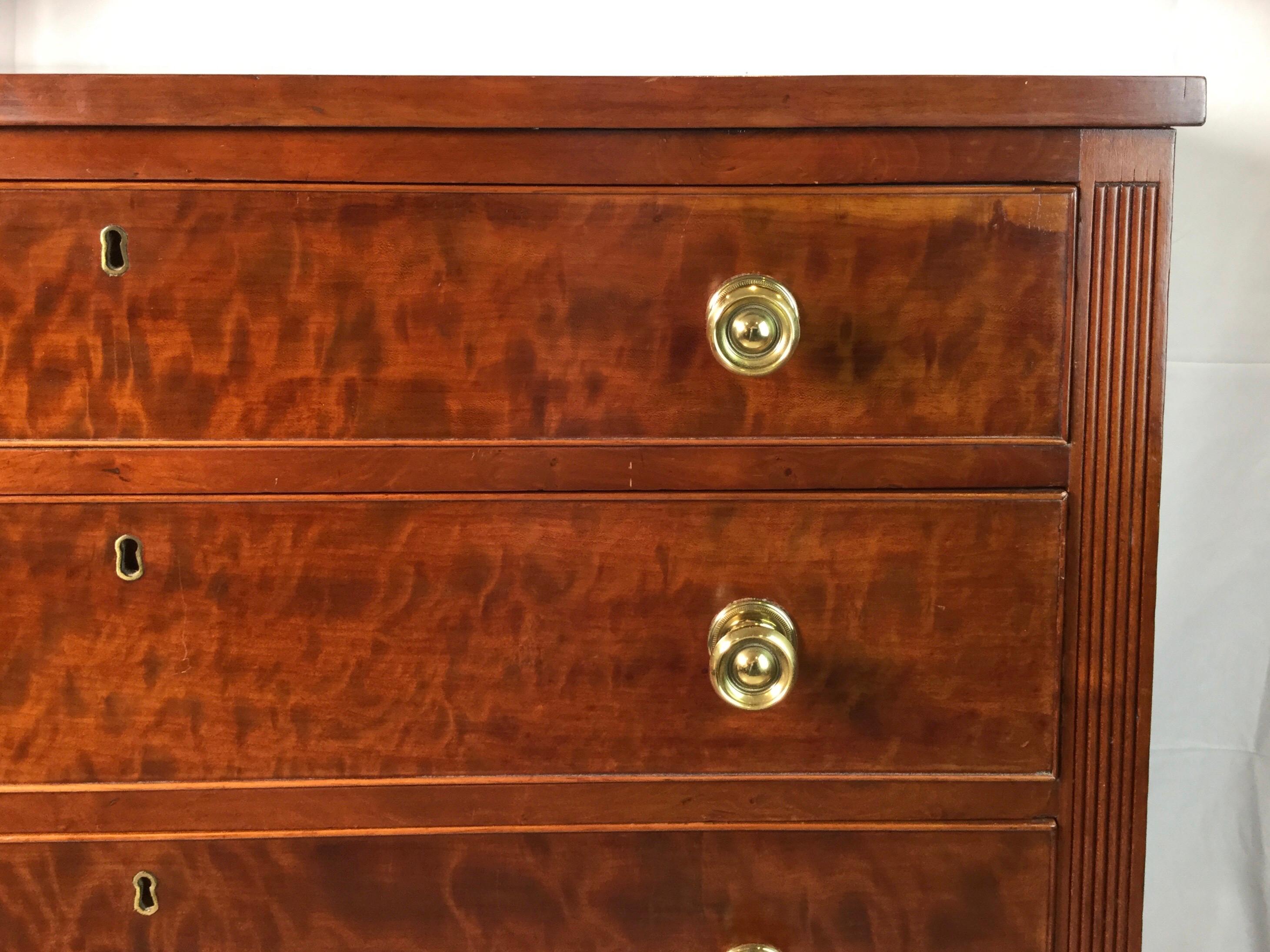 A beautifully figured cherry four-drawer chest with brass hardware. The chest with reeded posts resting on turned legs, American, circa 1810.