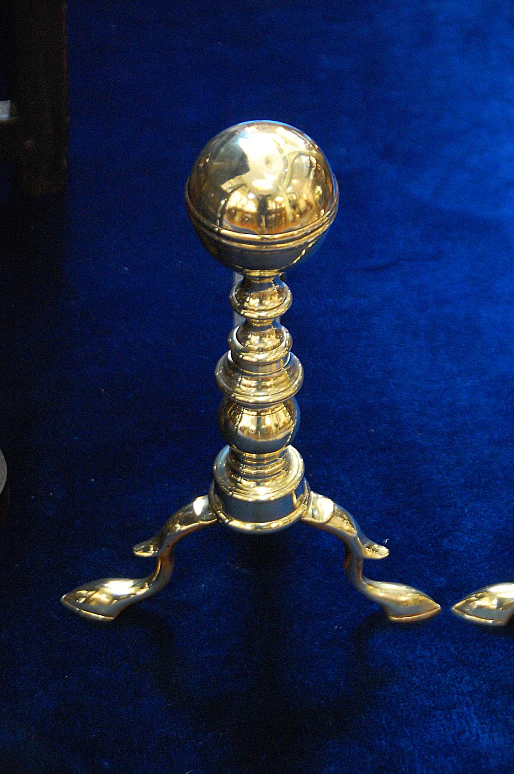 American pair of 18th century brass belted ball top andirons with original log stops and iron log carriers. These cast brass belted ball top andirons are seamed, have spurred cabriole legs and original belted ball top log stops. They most probably