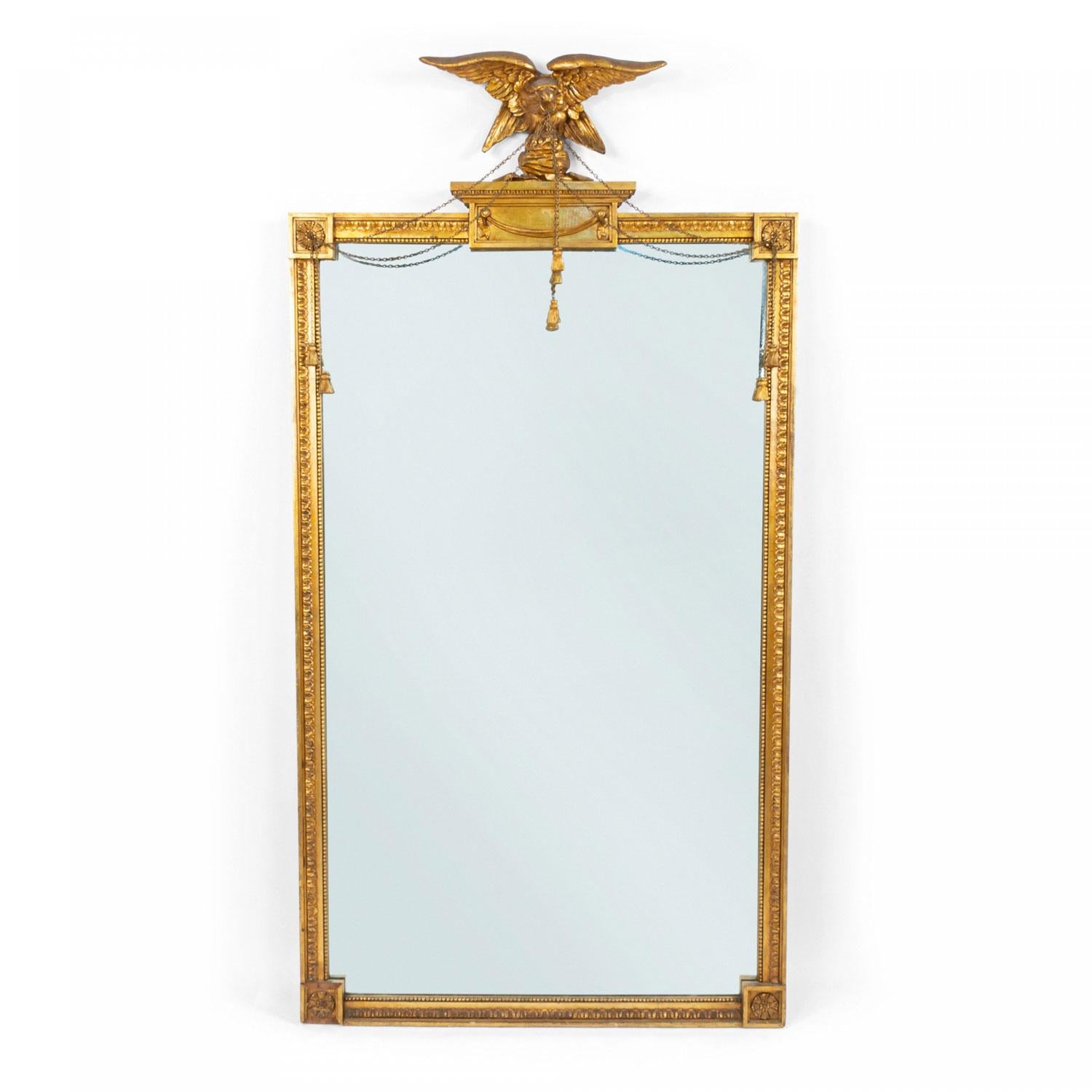 Miroir mural rectangulaire en bois doré, de style fédéral américain (19e siècle), surmonté d'une plate-forme à gradins avec un aigle sculpté et doré tenant des guirlandes de chaînes en métal.  sur un cadre en forme d'œuf et de fléchette avec des