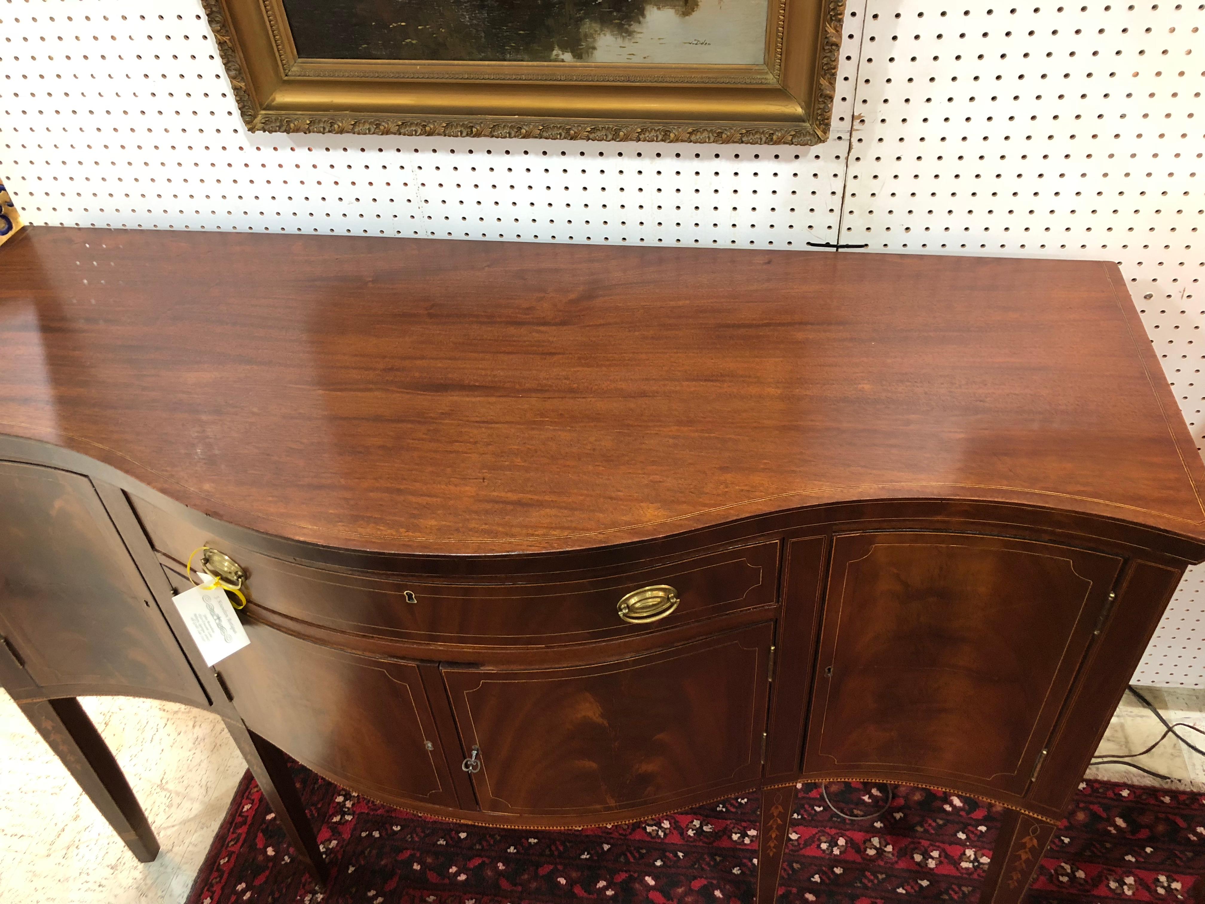 American Federal sideboard with fine inlaid bell flowers, line and tooth inlay. Tall and serpentine, with original brass ovals. Banded inlay on the legs. Original key, line inlay around the top edge. Excellent color and finish.