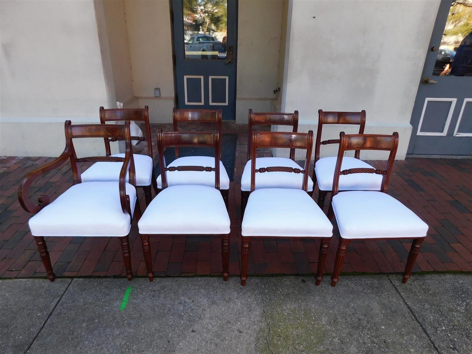 English Regency set of eight mahogany dining room chairs with scrolled crest rails and arms, rectangular splat backs, barley twist spindles, white muslin seats, and resting on the original bulbous ringed reeded legs with splayed rear legs, early