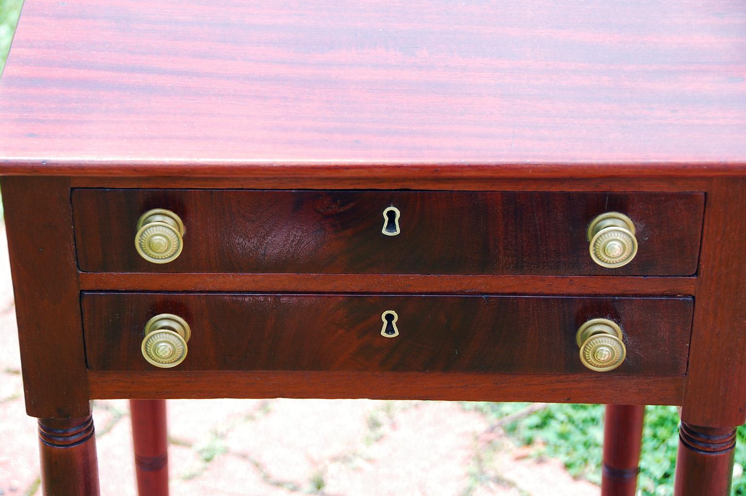 American federal mahogany two drawer worktable with flame grain mahogany drawer fronts, slim turned tapered legs with ring detailing.  This table was probably made in Newburyport, Massachsetts. This simple yet elegant table has a visual delicacy