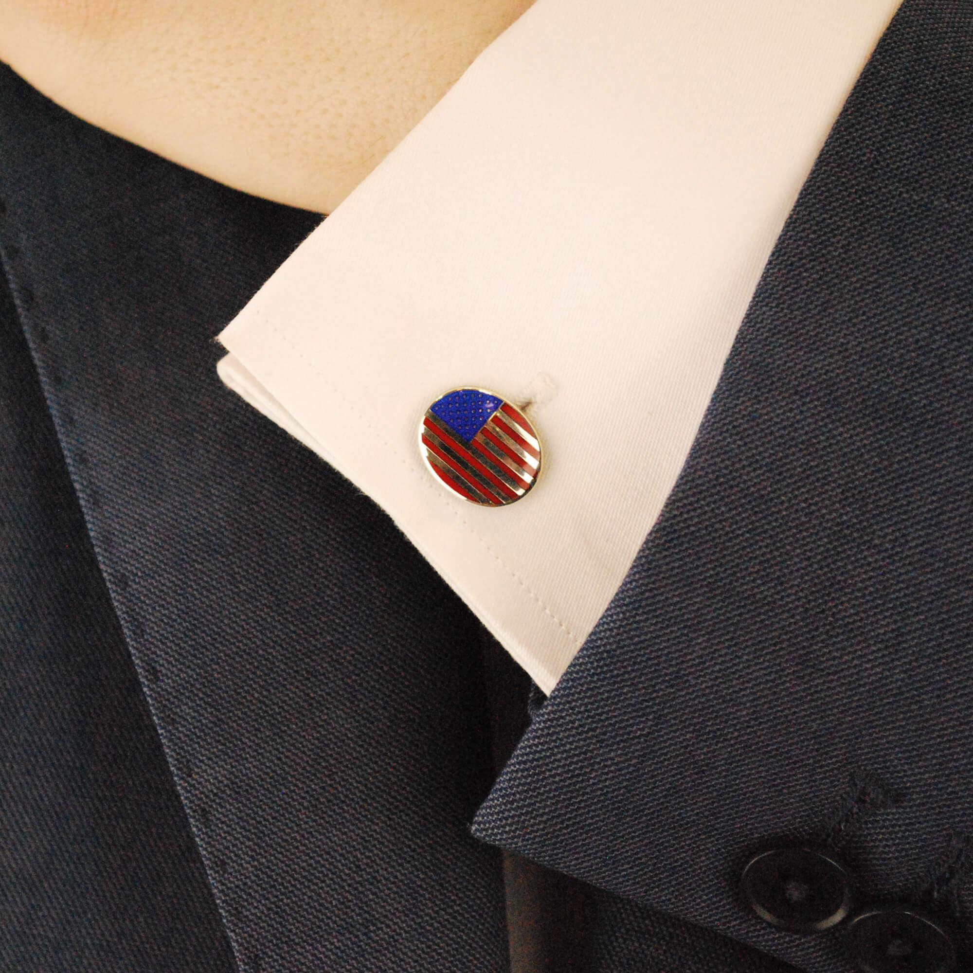 A pair of enamel oval cufflinks in sterling silver. 
Each cufflink is designed as a sterling silver plaque decorated with red and blue enamel depicting the American flag, secured to reverse with a post and swivel back fitting. Dimensions: 1.7x1.4cm.