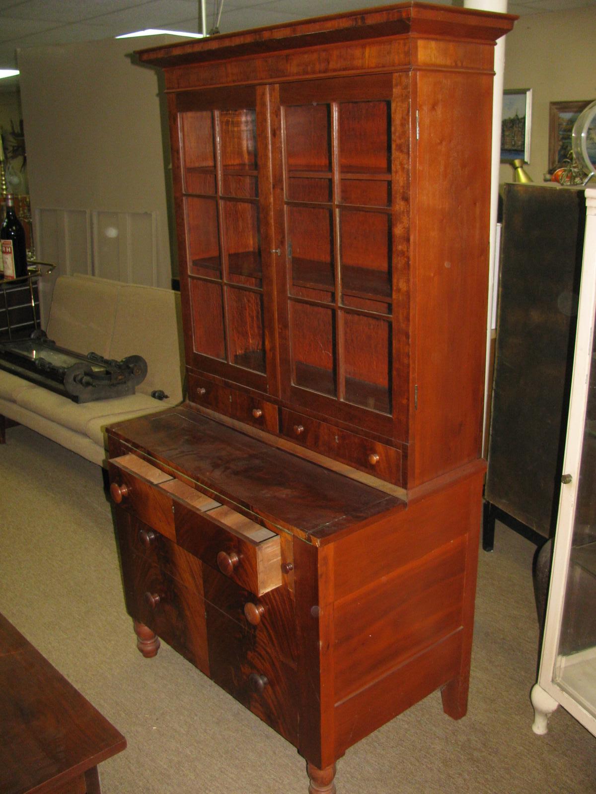 Period 1850 American Empire secretary desk in flame mahogany. Two-door bookcase, two small drawers below with orig key and lockset sits on base which consists of a desk which opens out to 32in., below the desk is 3 drawers with orig. pulls. All in