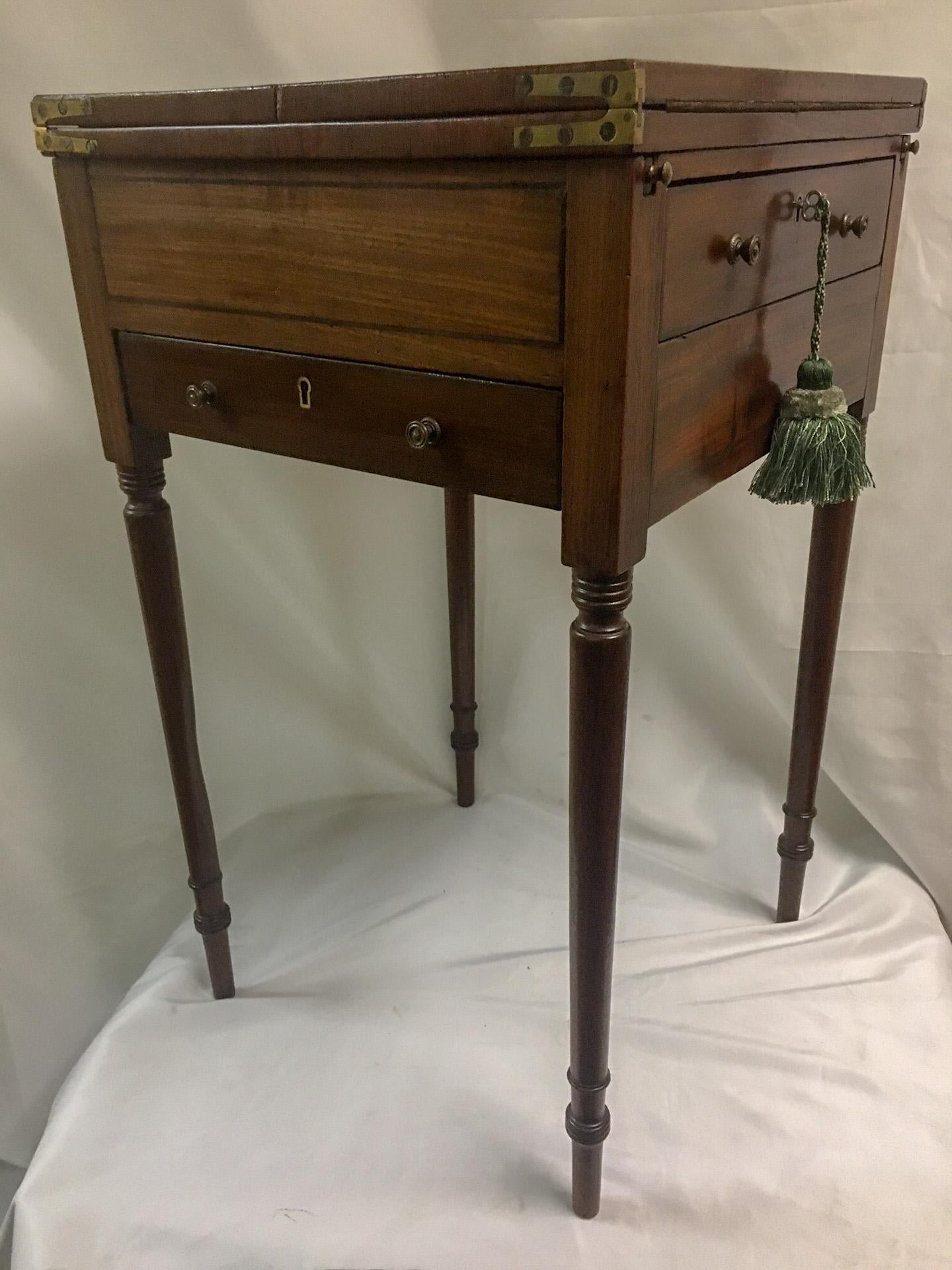 This unusual American mahogany petite sized writing table features two flip-top panels with leather inserts and two compartmentalized drawers, one in front and one on the side. The drawers are dovetailed, the brass hardware is original and the