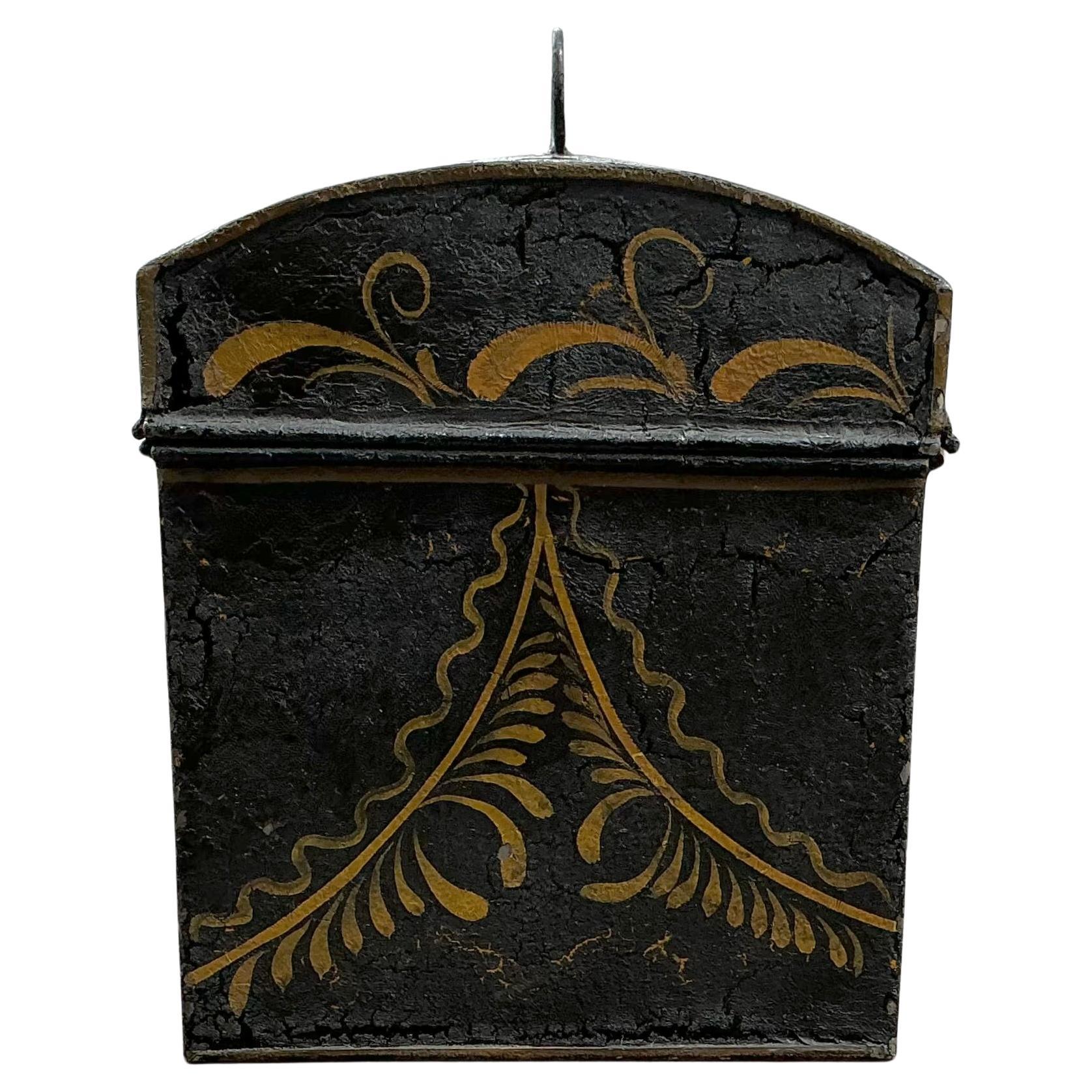 Charming American Toleware Tin Box. Box is hand-painted in vivid folk art floral motifs of red, gold, and green against a deep black background. The domed lid features an oval black tin handle, and the front of lid retains the front portion of its