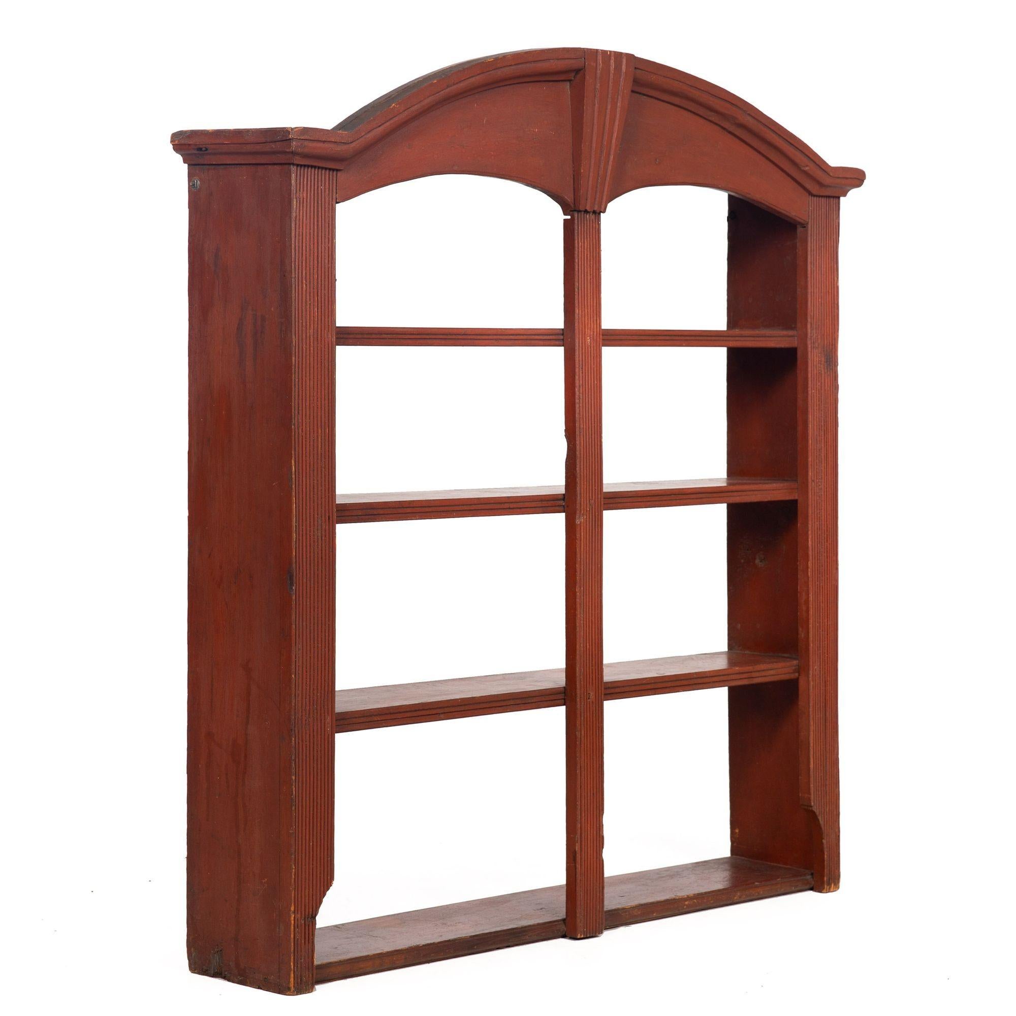 AMERICAN RED-PAINTED HANGING WALL SHELF
Probably Pennsylvania circa the first half of the 19th century
Item # 310ZPI05Q 

A compelling and most useful open bookcase, the simple and austere form features an arched and molded cornice around a central