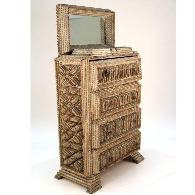 An American tramp art miniature dresser in cut and painted wood with four drawers and an inset mirror. Can be used easily as a jewelry box. Made in the 1920s. Original patina; no marks or signature.