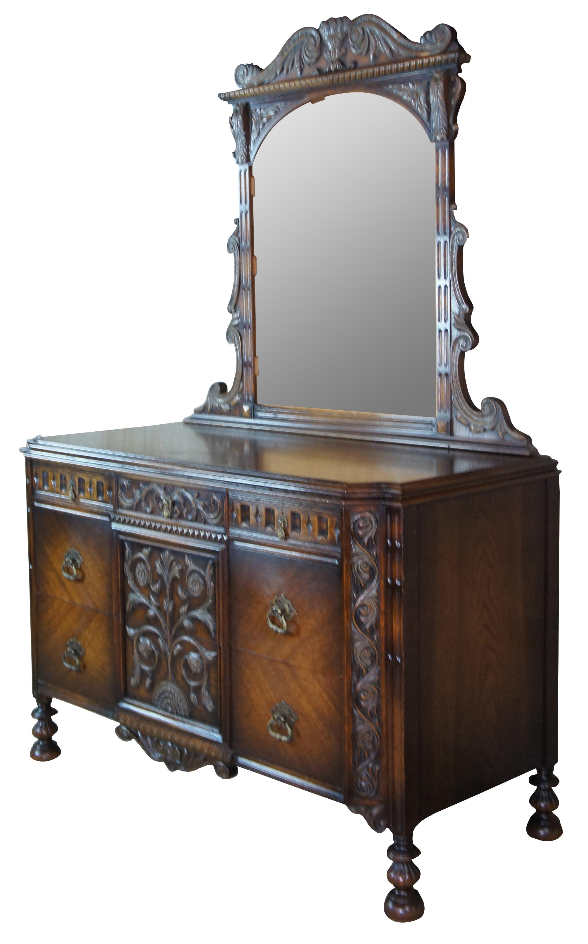 American Furniture Company Gothic or Spanish Renaissance Revival vanity dresser or chest of drawers. Made from american oak with low relief floral acanthus carvings, an arched and scrolled mirror, turned legs and bun feet. Includes five drawers.
