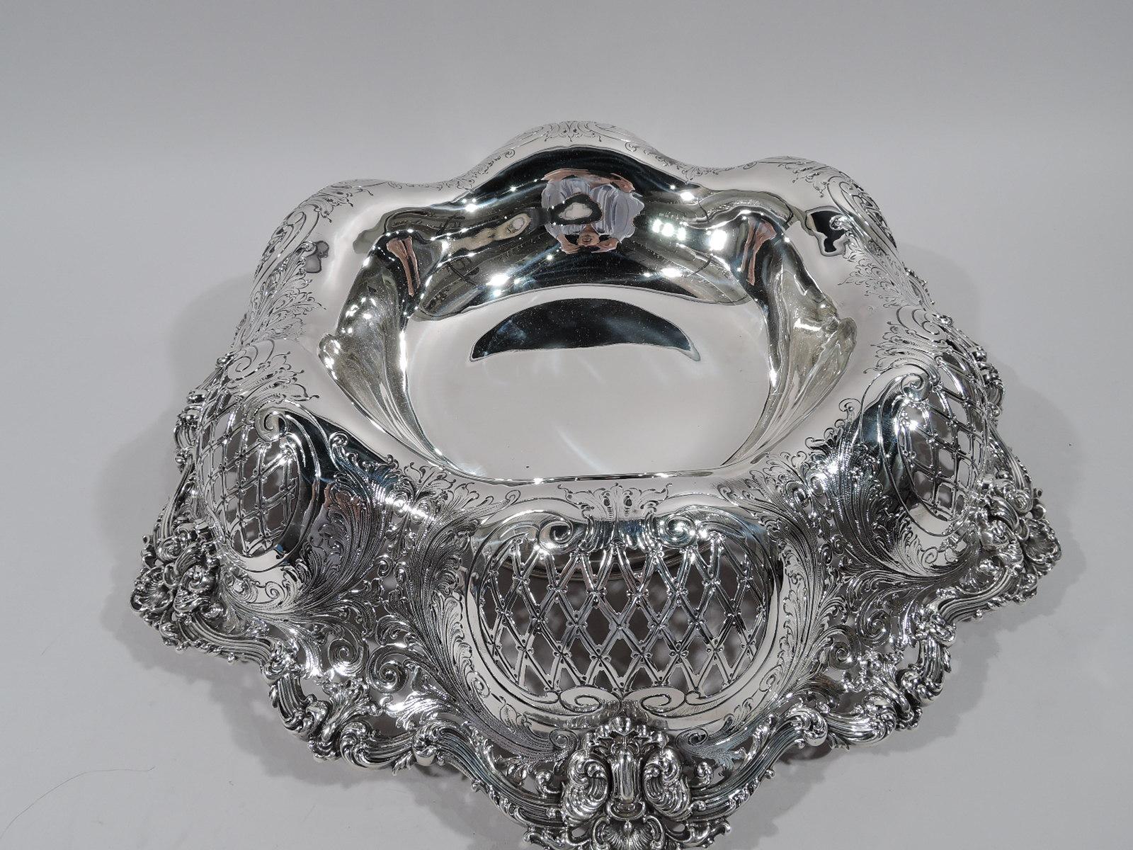 Gilded Age sterling silver centerpiece bowl. Made by Redlich in New York, ca 1900. Round solid well. Sides lobed and turned-down with pierced diaper in engraved leafy scrolled frames. Rim has reeded leaf-capped scrolls interspersed with leaves and