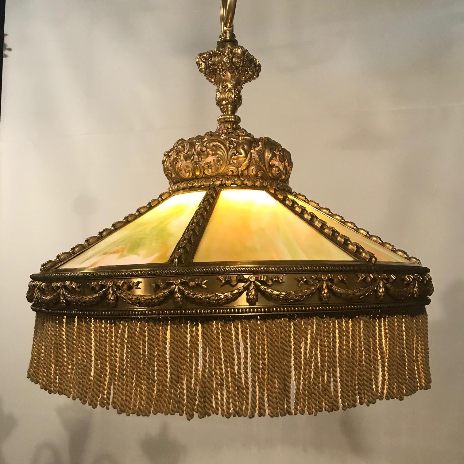 Esta imponente luminaria combina un dosel de bronce dorado perforado de muy buena calidad y una montura central, fundida con putti, máscaras y acantos en volutas. Mira con atención  en las fotos detalladas para hacerte una idea de la calidad de los